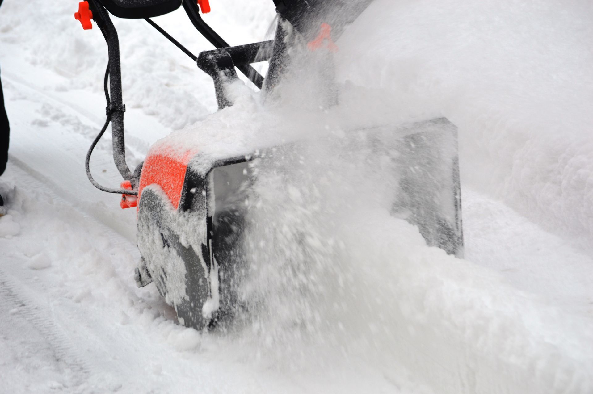 A person is using a snow blower to remove snow from a road.