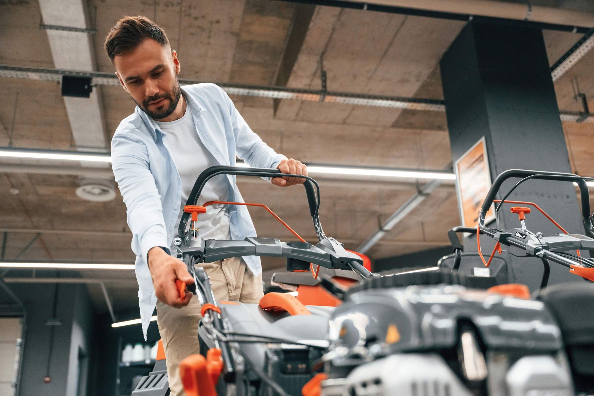 A man is in a new lawn dealer purchasing a big lawn mower.