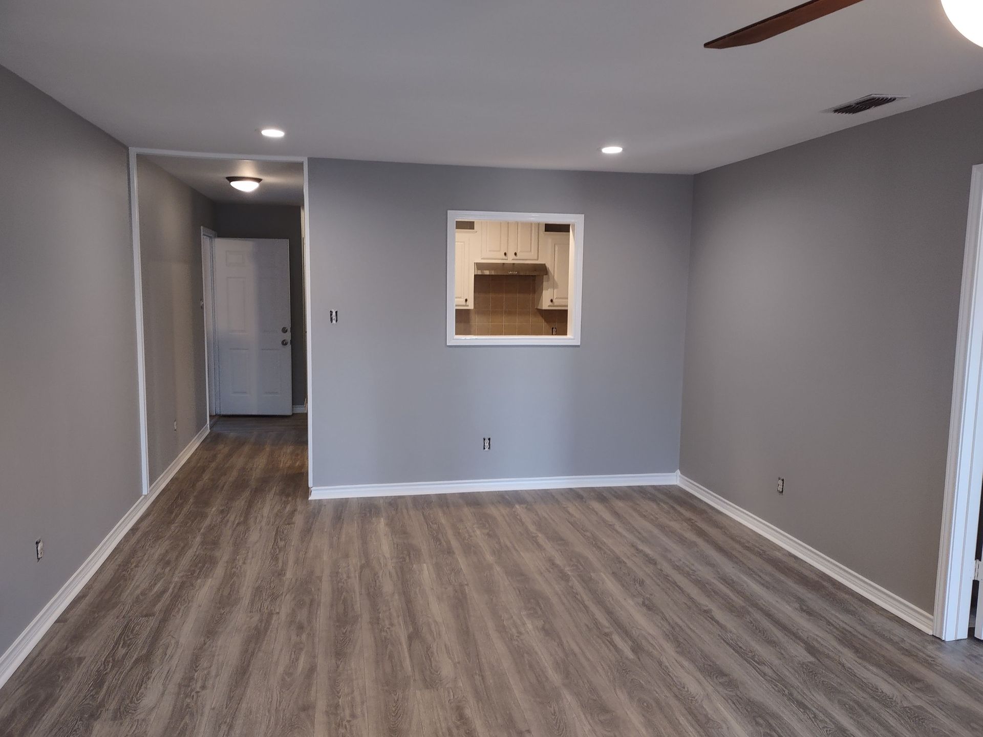 An empty living room with hardwood floors and a ceiling fan