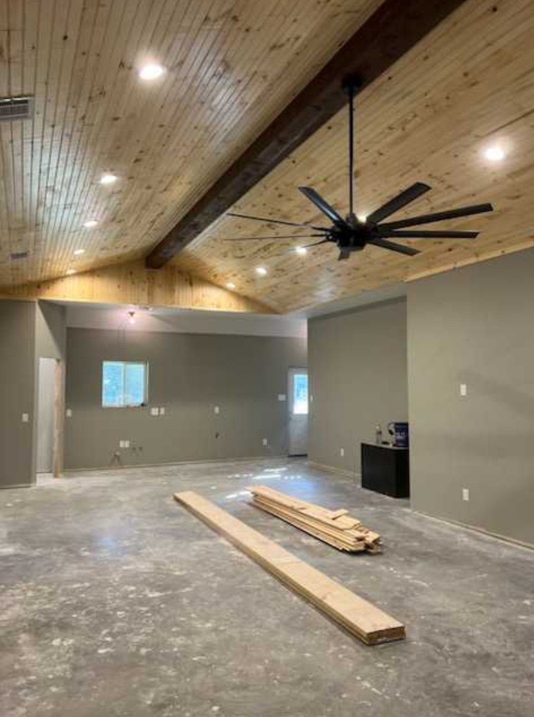 A large empty room with a wooden ceiling and a ceiling fan.