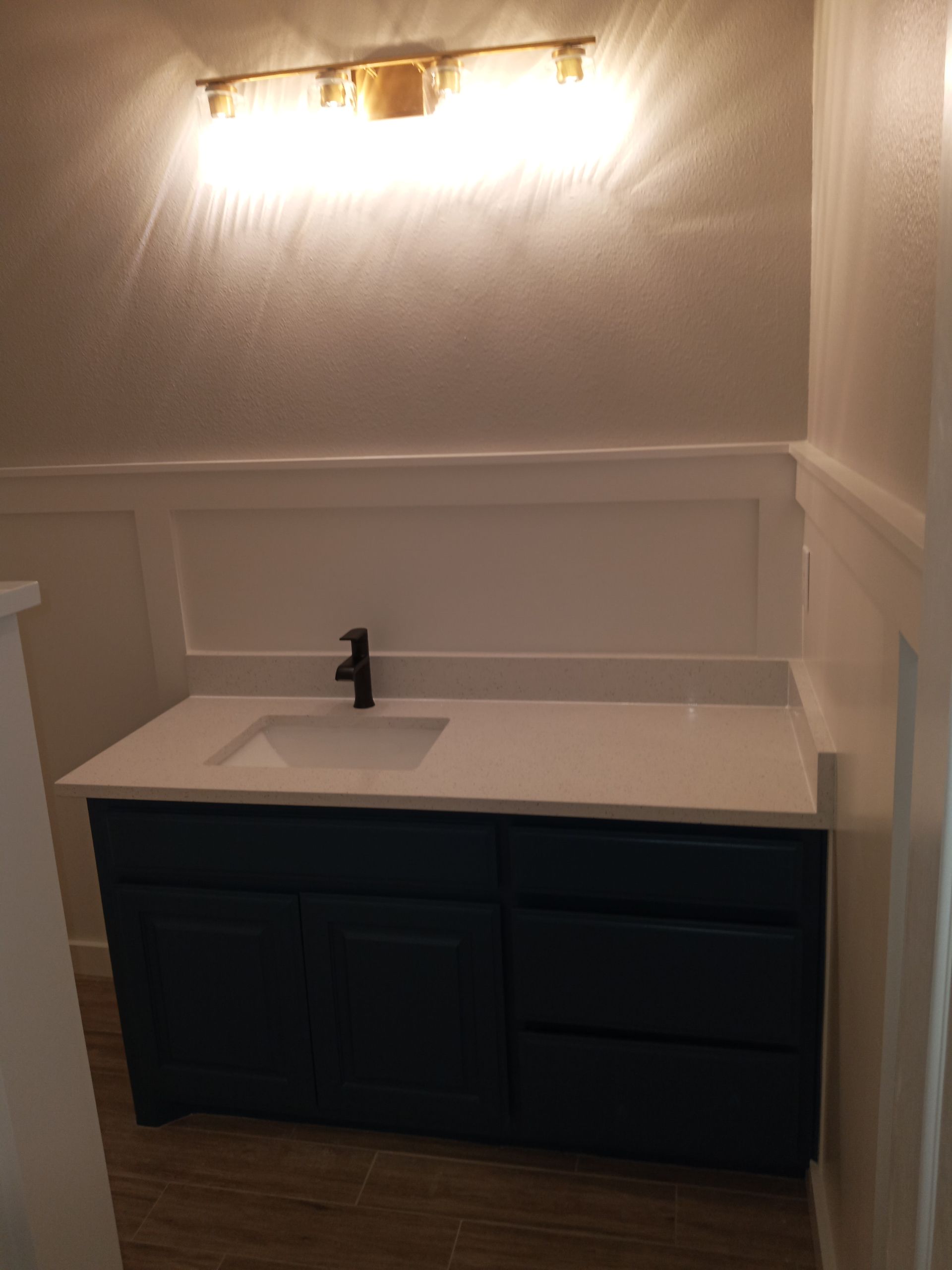 A bathroom with a blue vanity and a sink.