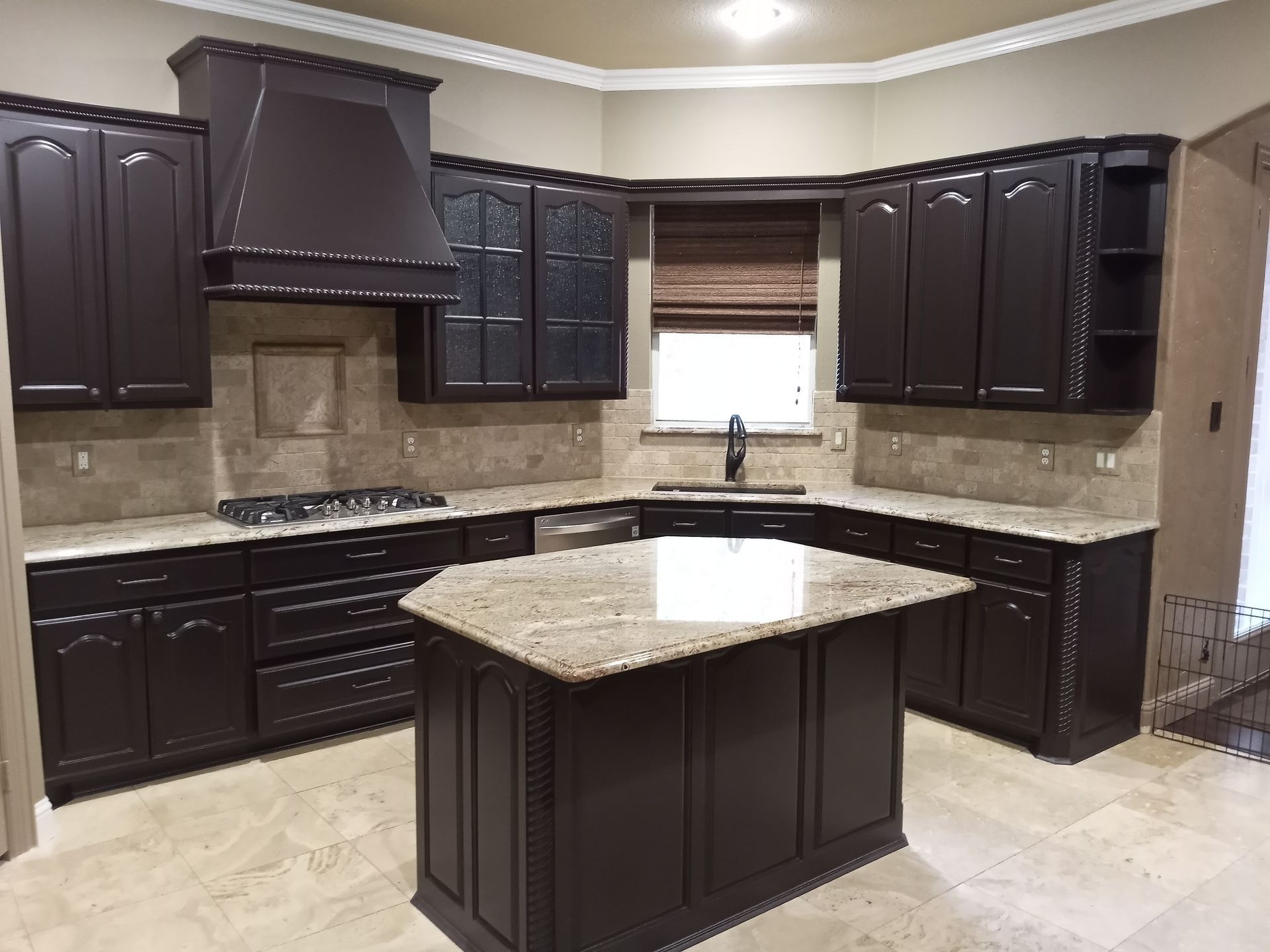 A kitchen with black cabinets and a large island in the middle.