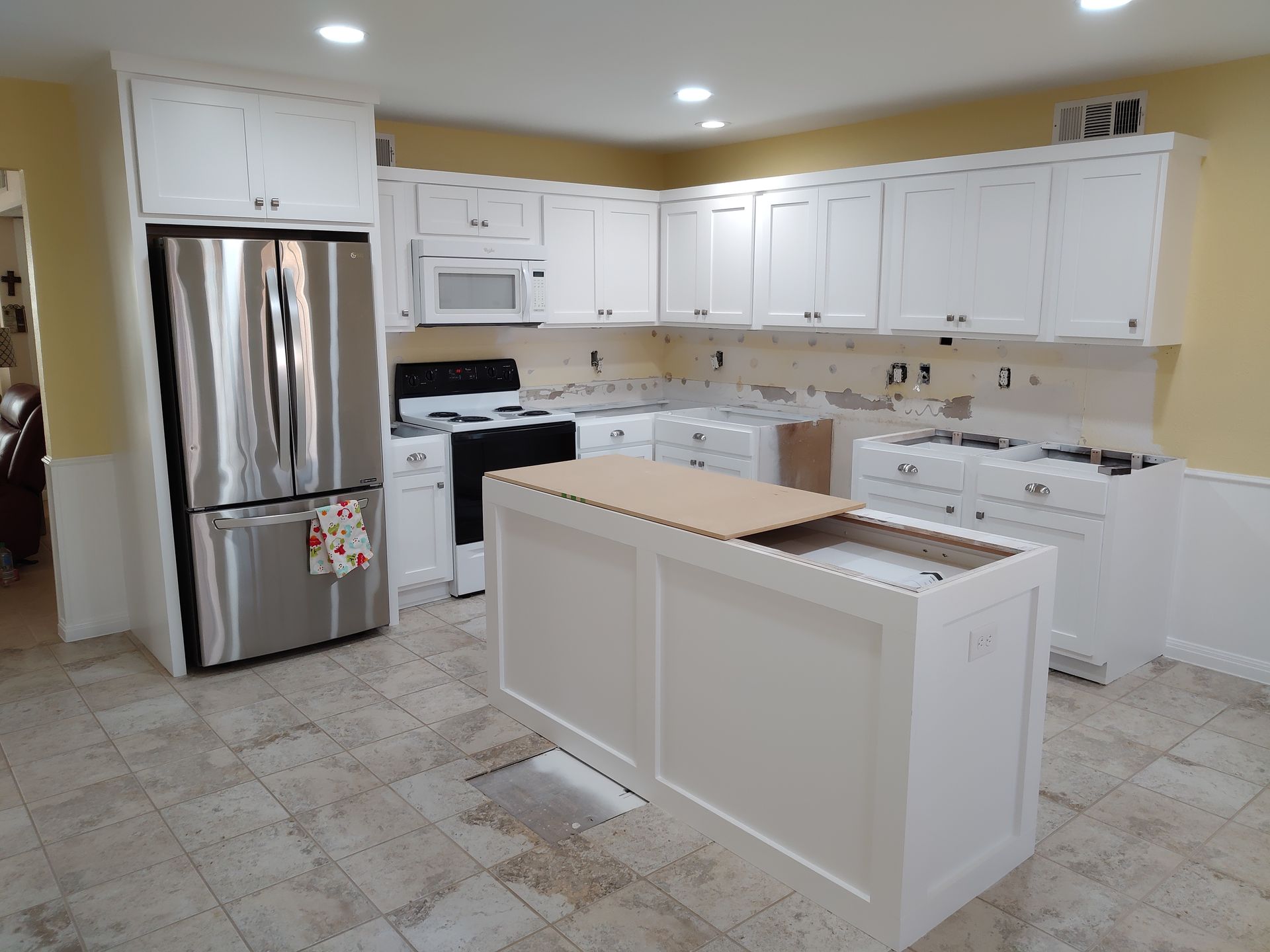 A kitchen with white cabinets and a stainless steel refrigerator.
