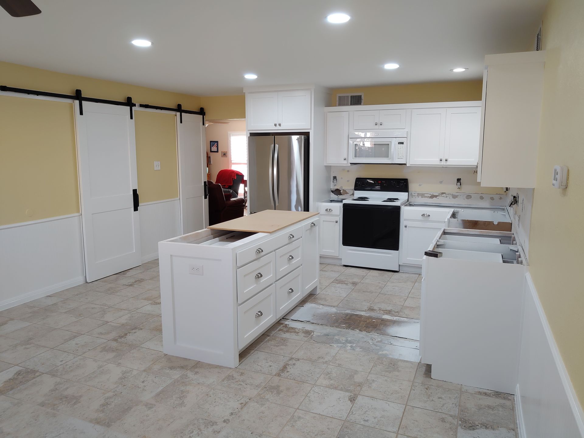 A kitchen with white cabinets and a large island in the middle