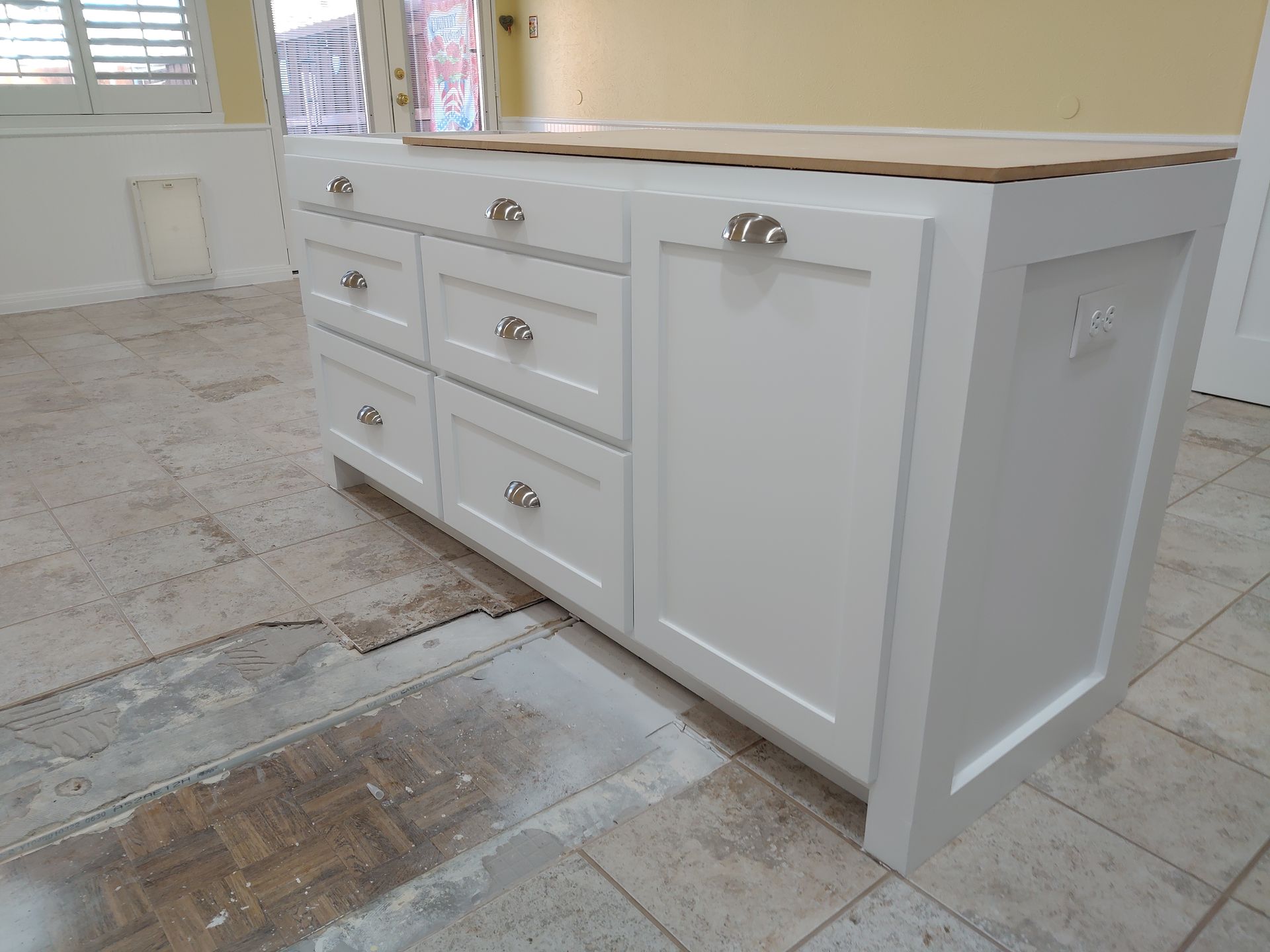A white cabinet with drawers is sitting on a tiled floor.