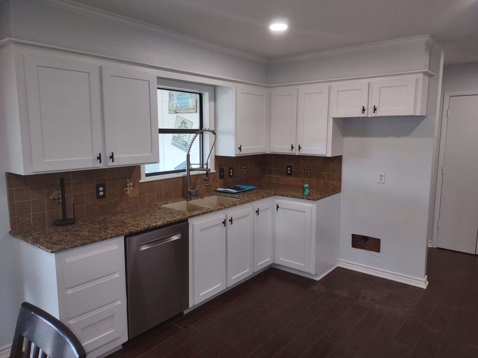 A kitchen with white cabinets , granite counter tops , and a stainless steel dishwasher.