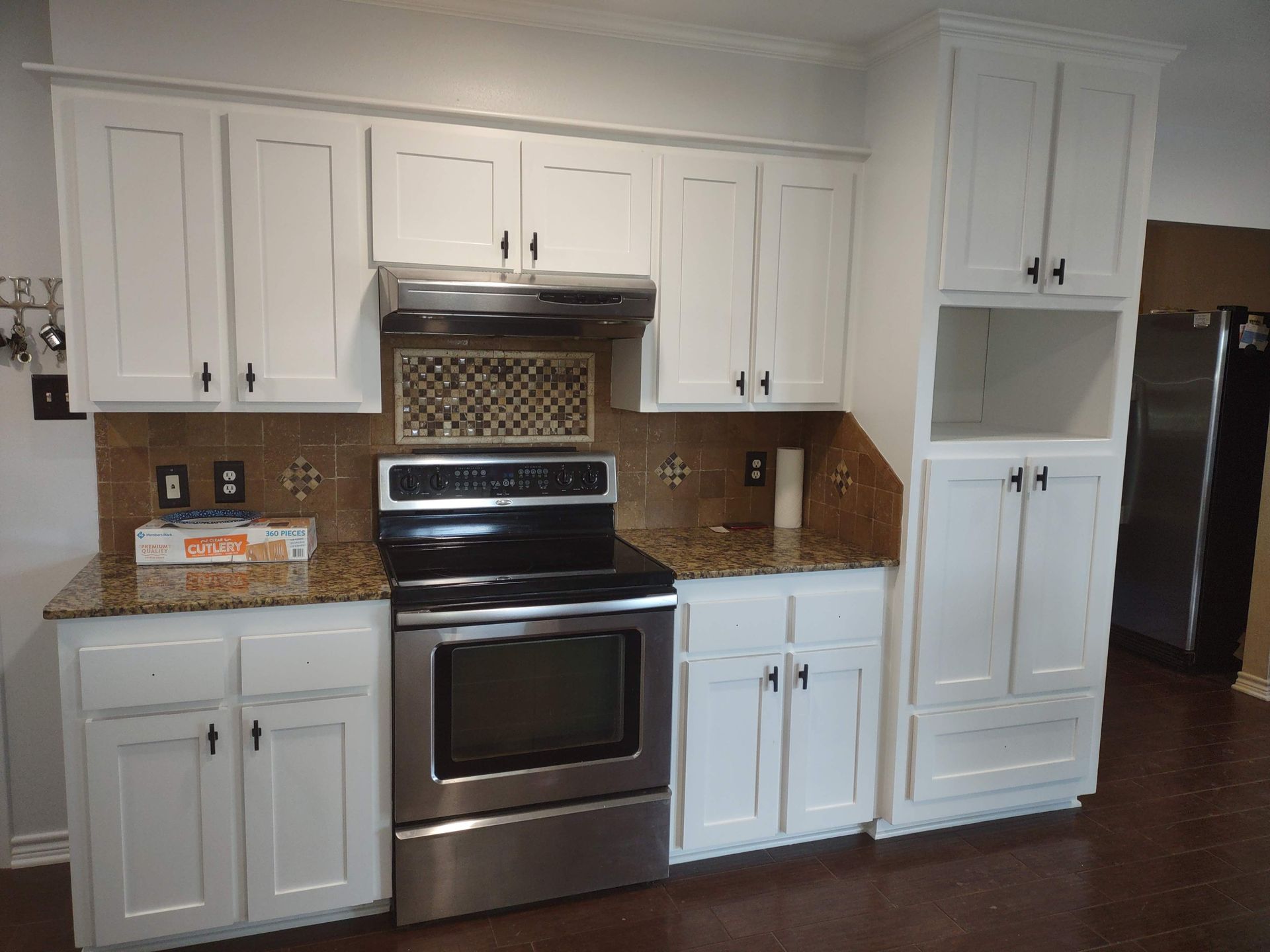 A kitchen with white cabinets , stainless steel appliances and granite counter tops.