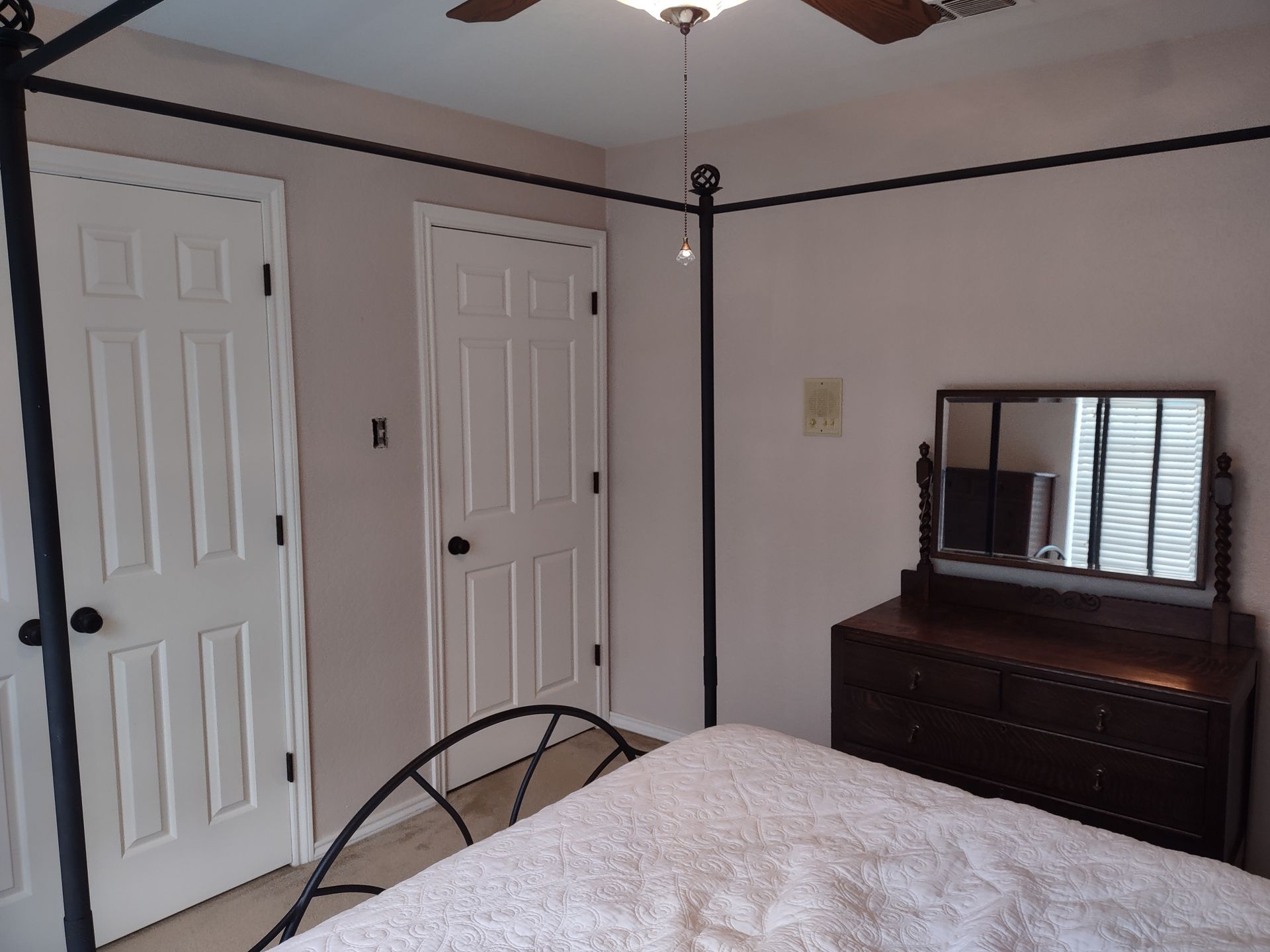 A bedroom with a four poster bed dresser and mirror