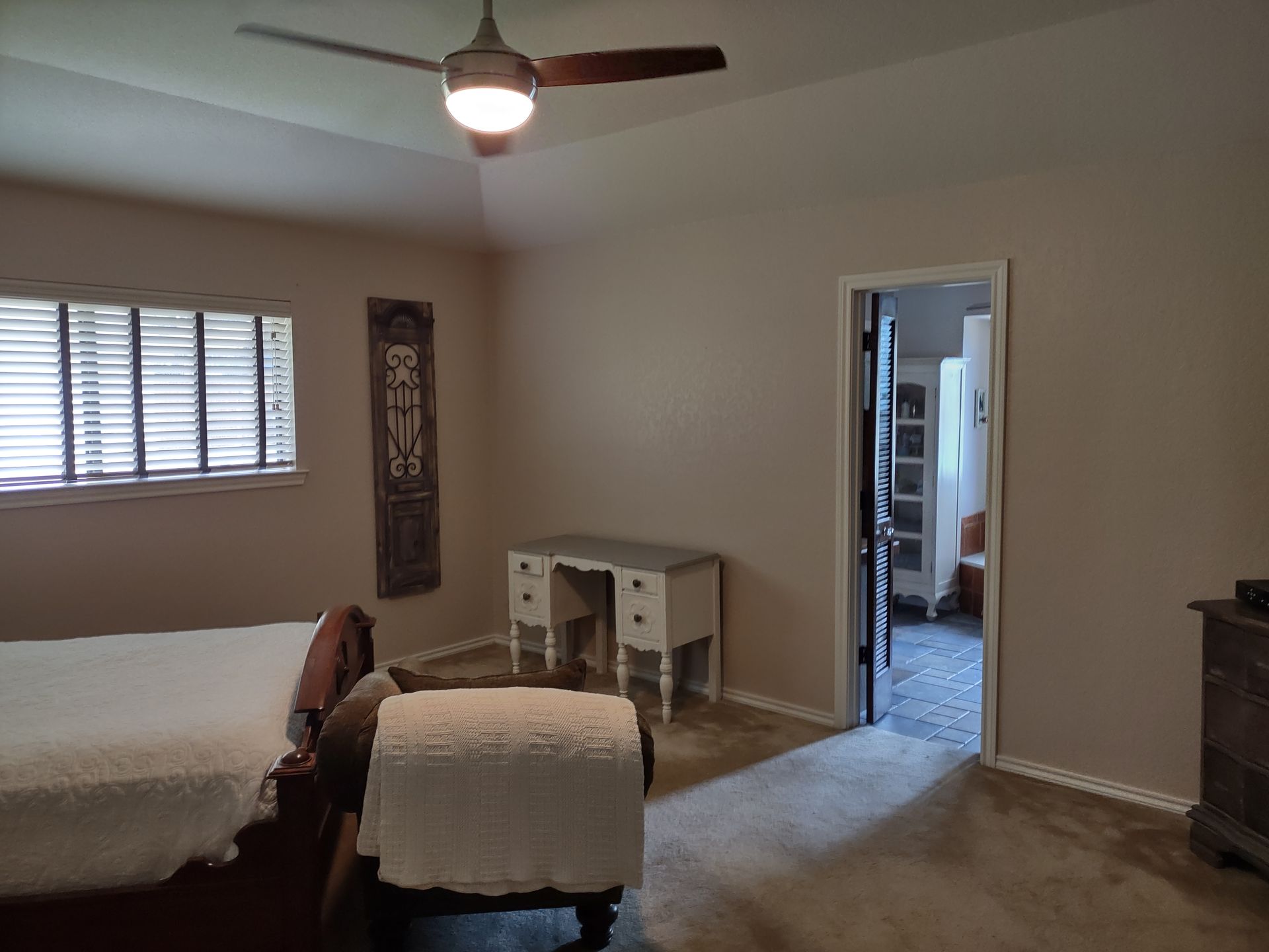 A bedroom with a bed , desk and ceiling fan.