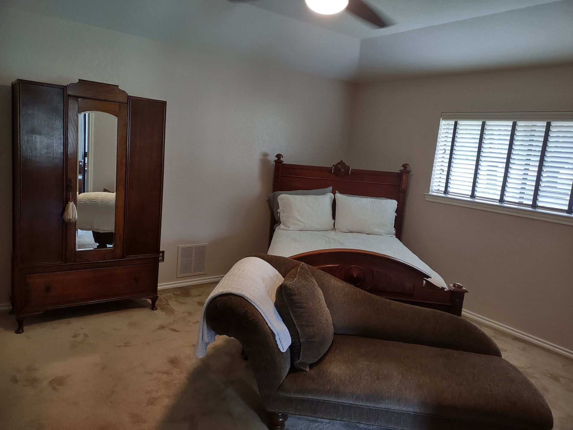 A bedroom with a bed and a chaise lounge