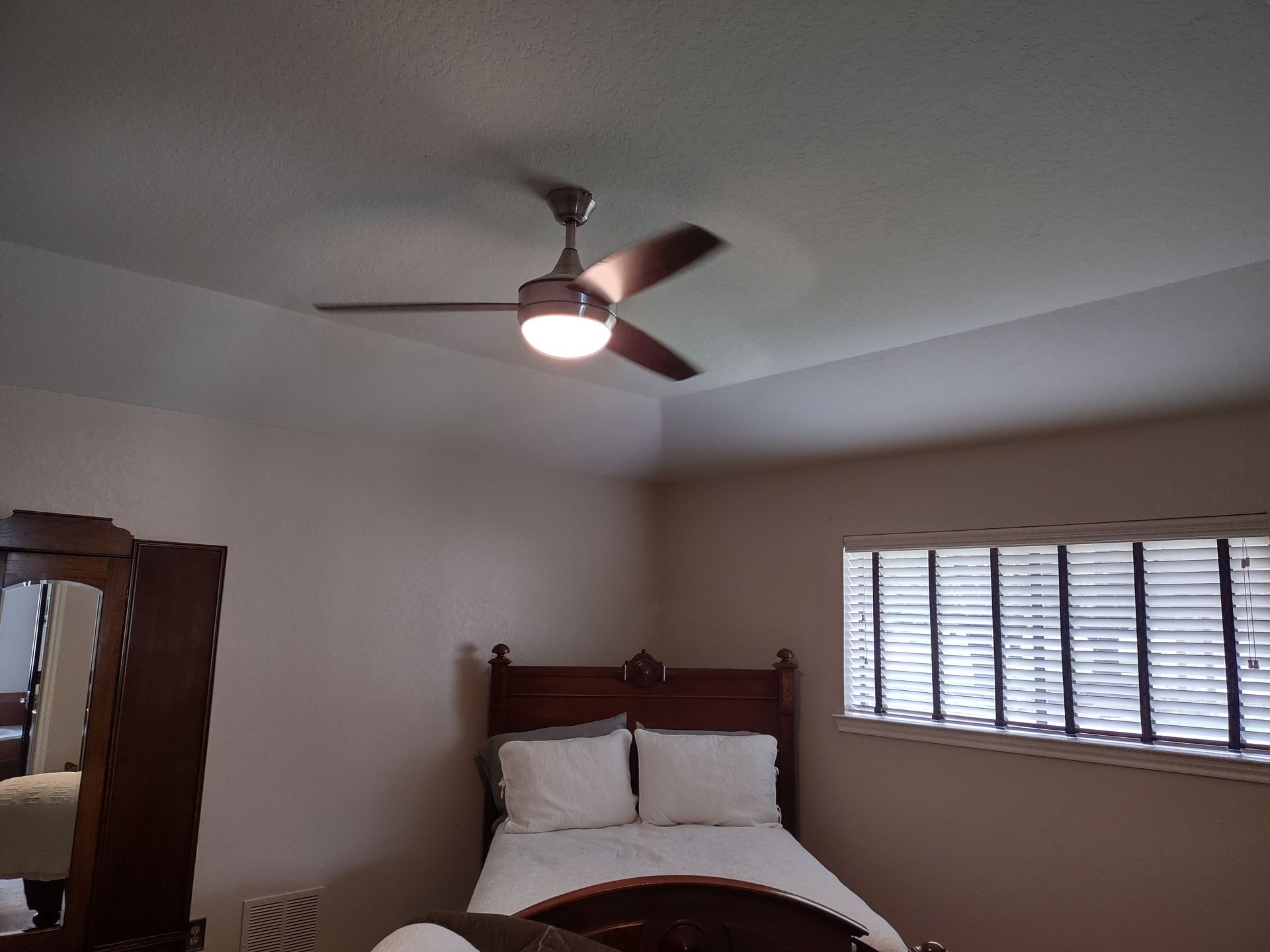A bedroom with a bed and a ceiling fan