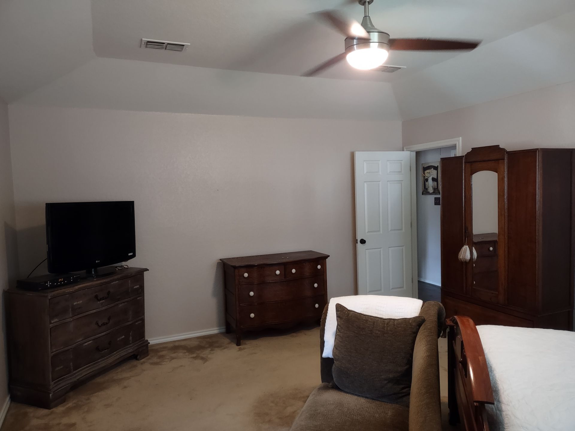 A bedroom with a ceiling fan and a flat screen tv