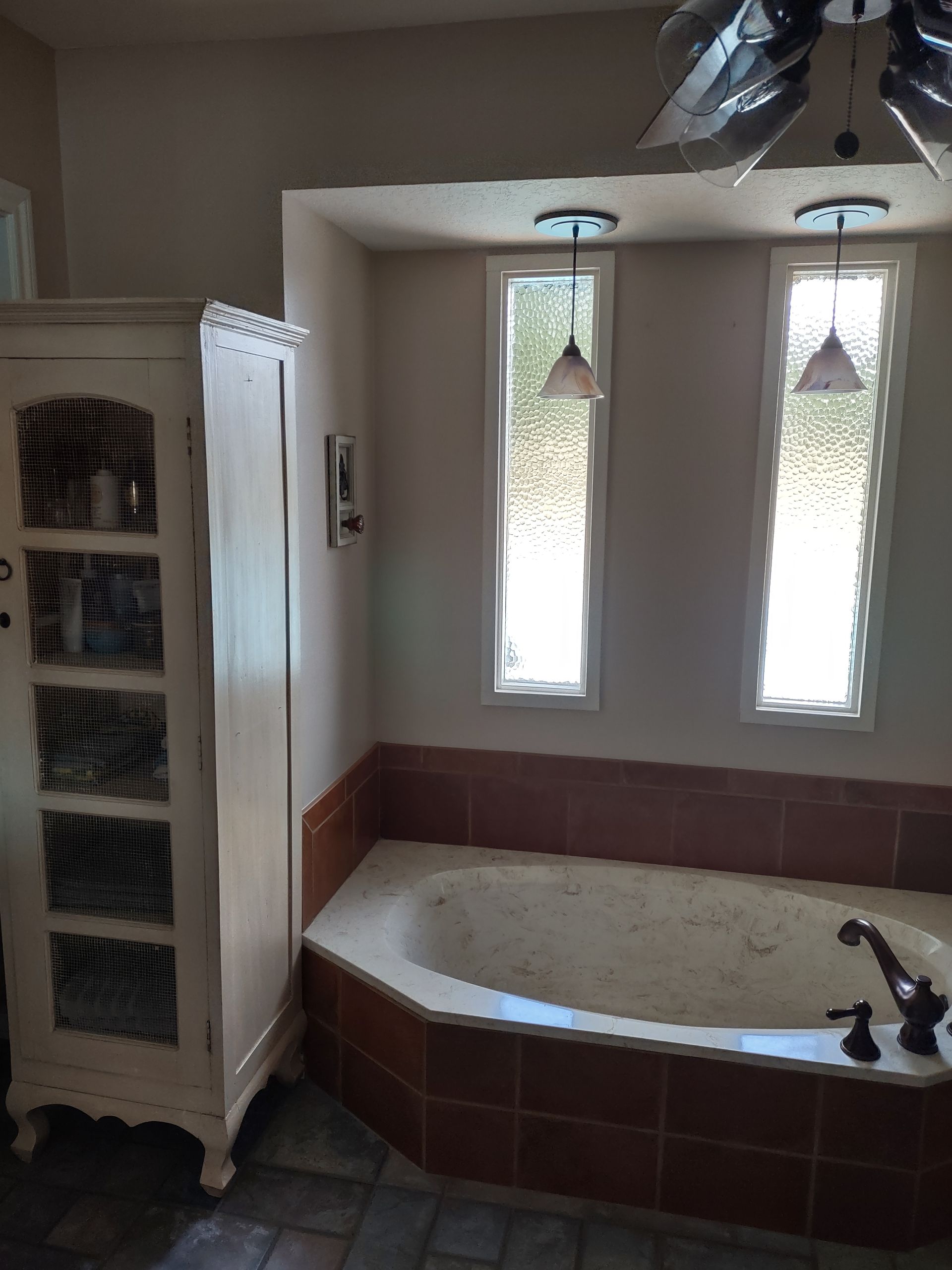 A bathroom with a tub and a ceiling fan