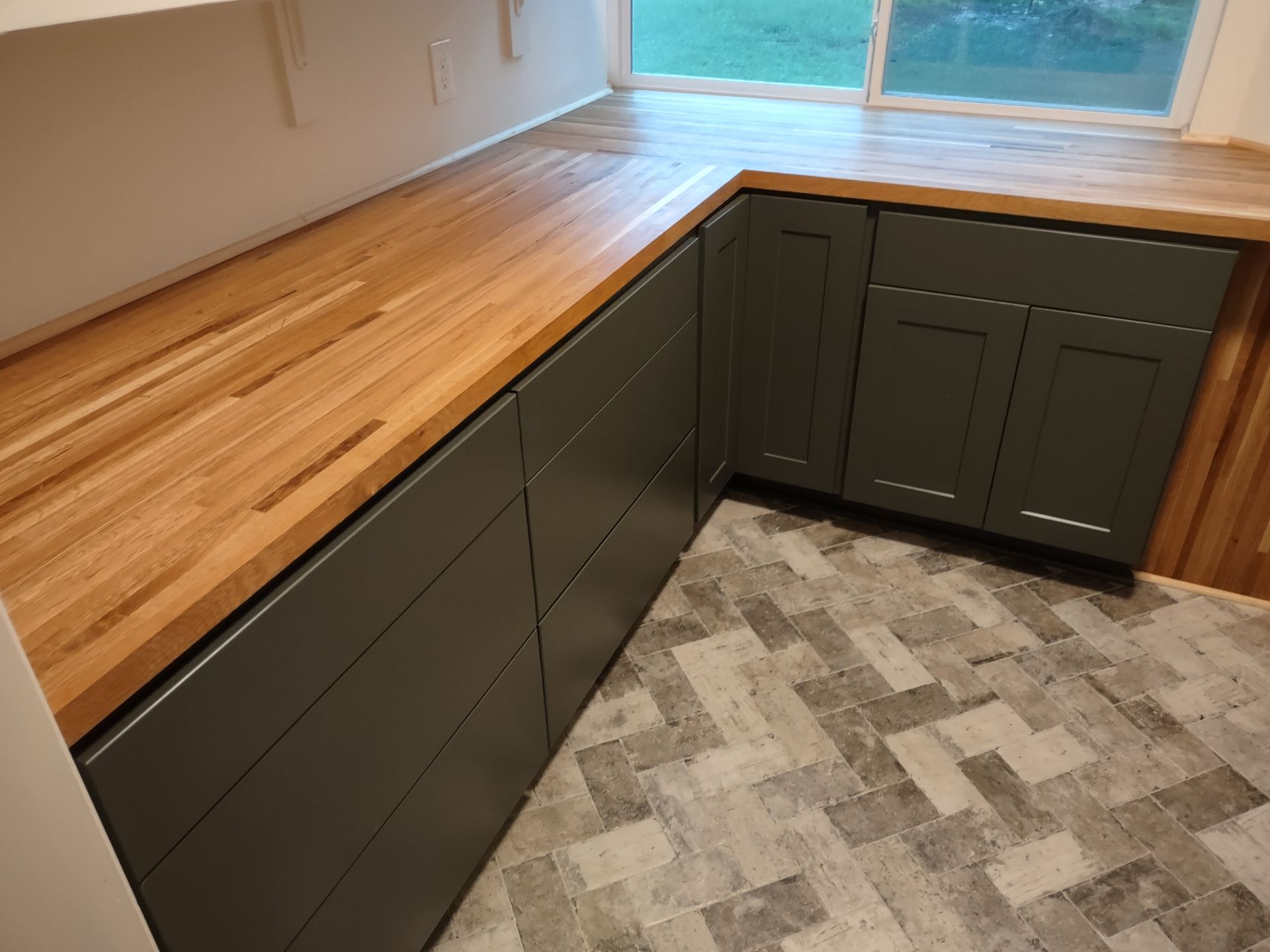 A kitchen with a wooden counter top and gray cabinets.