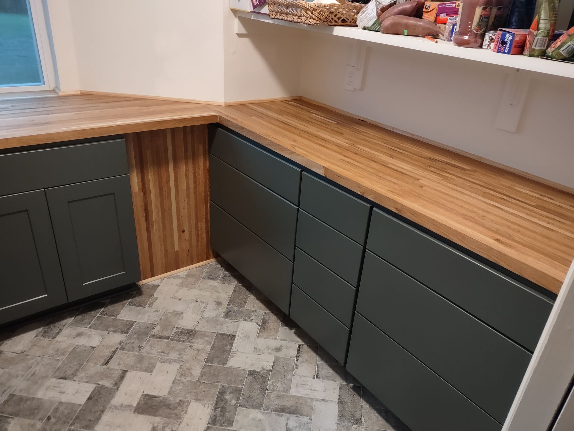 A kitchen with a wooden counter top and gray cabinets.