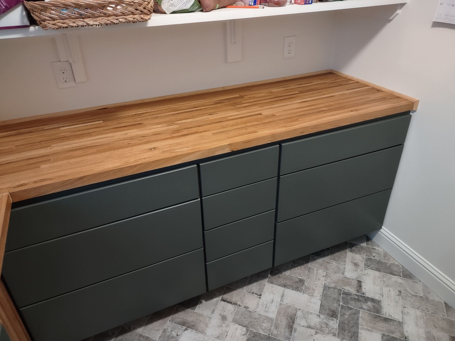 A laundry room with a wooden counter top and drawers.