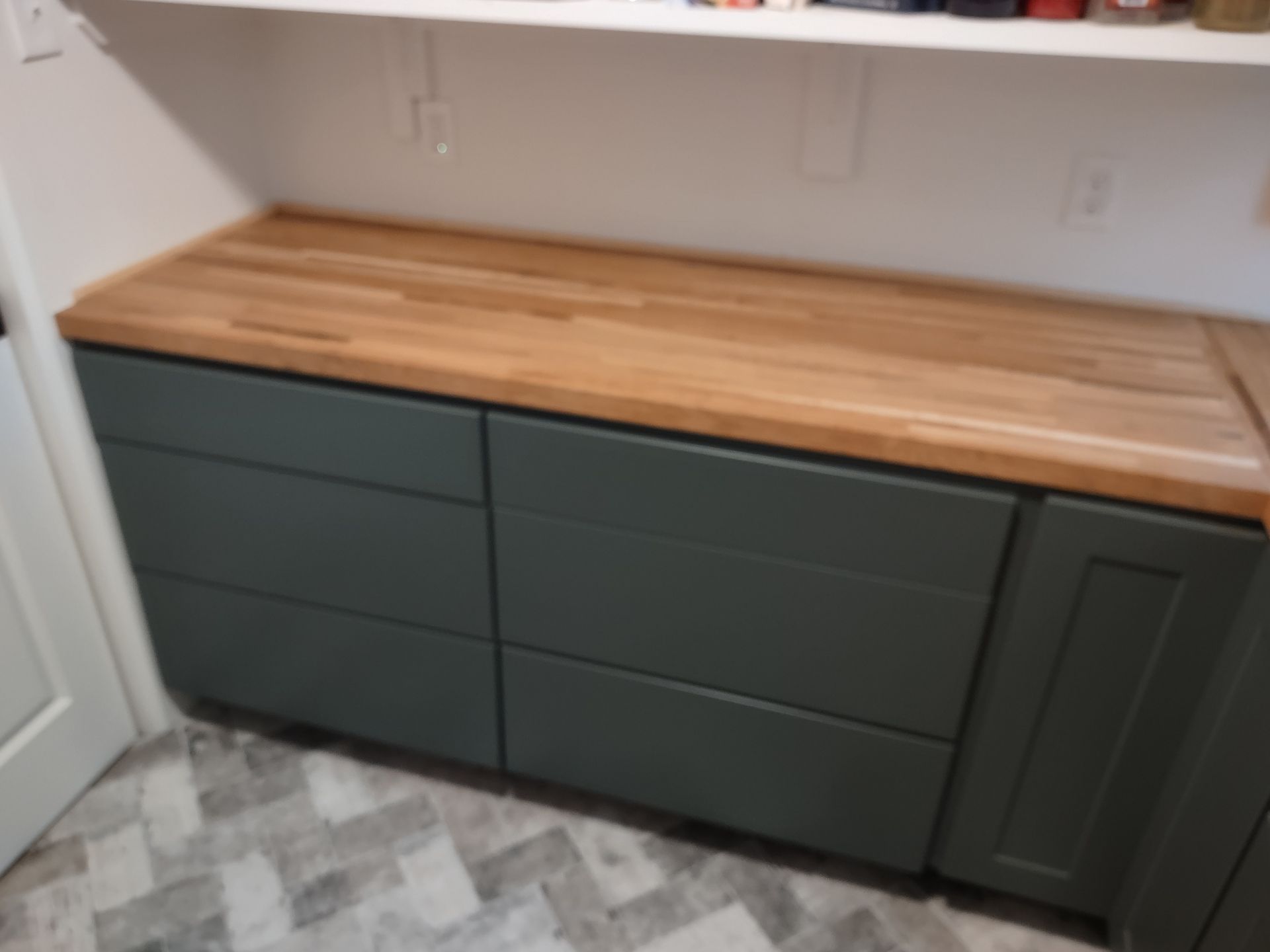 A kitchen with green cabinets and a wooden counter top