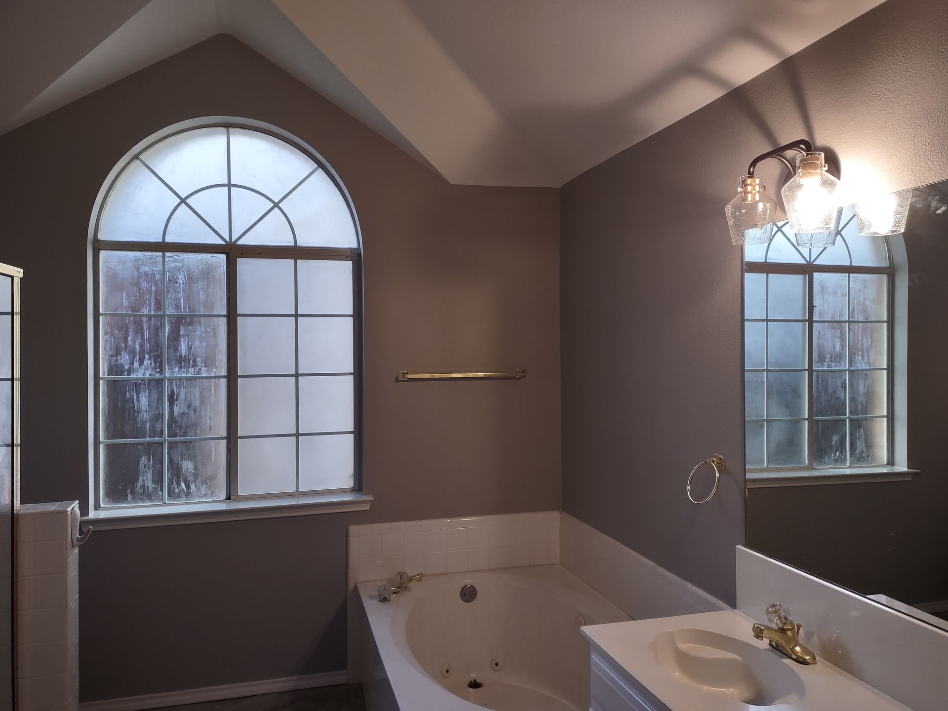 A bathroom with a tub a sink and two windows