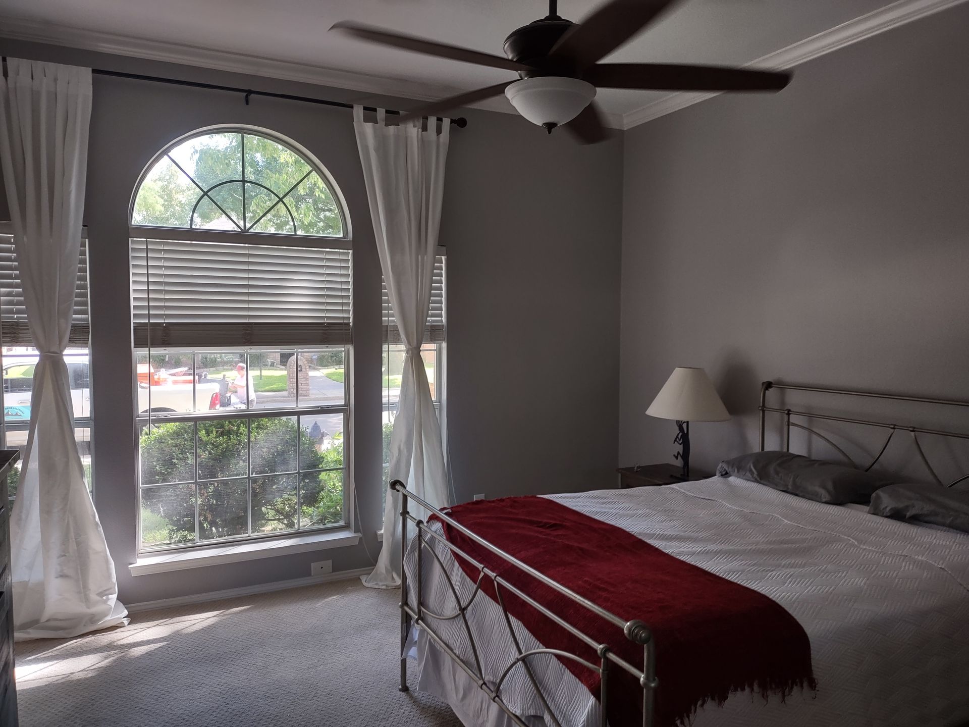A bedroom with a bed and a ceiling fan