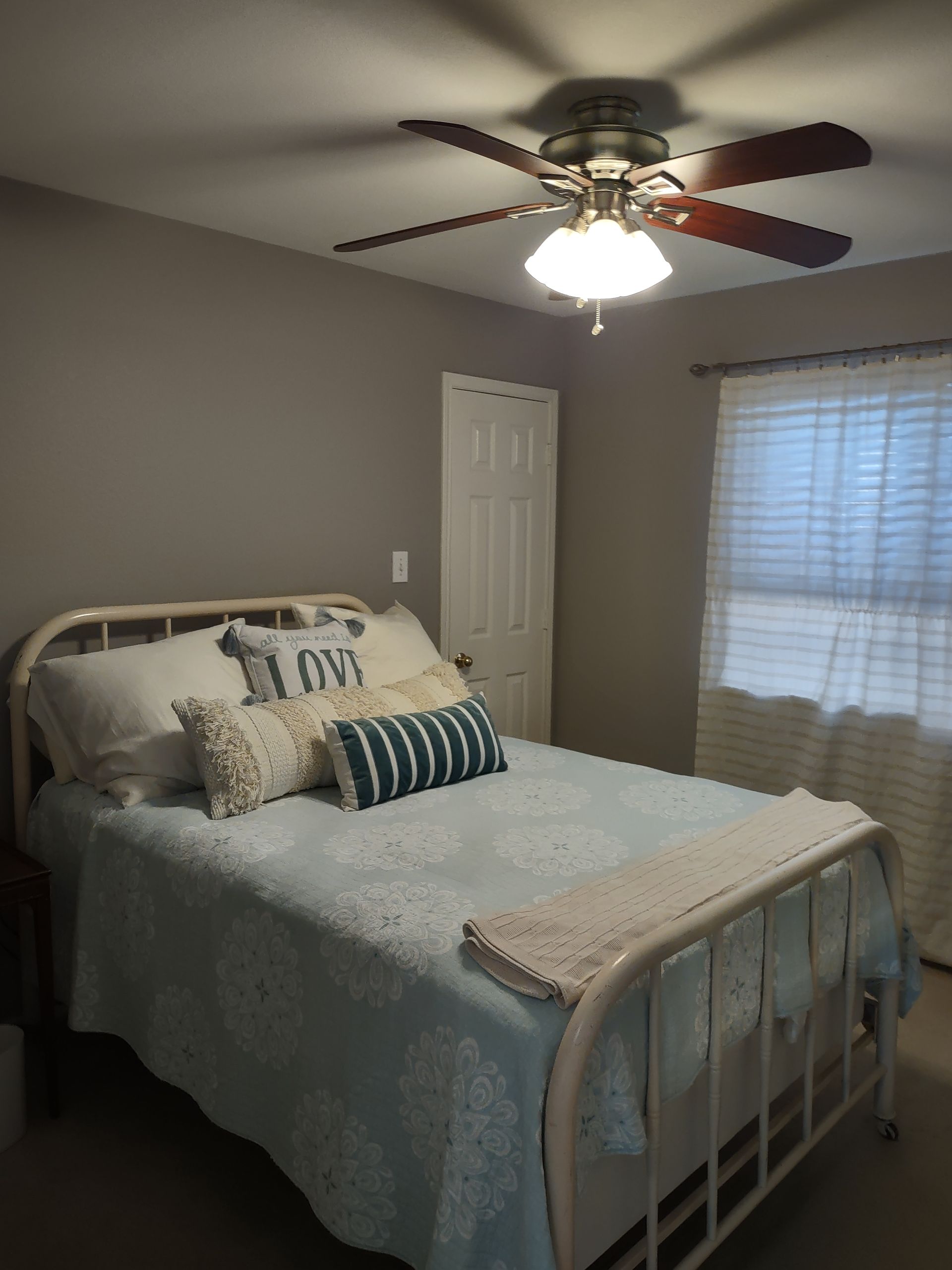 A bedroom with a bed and a ceiling fan.