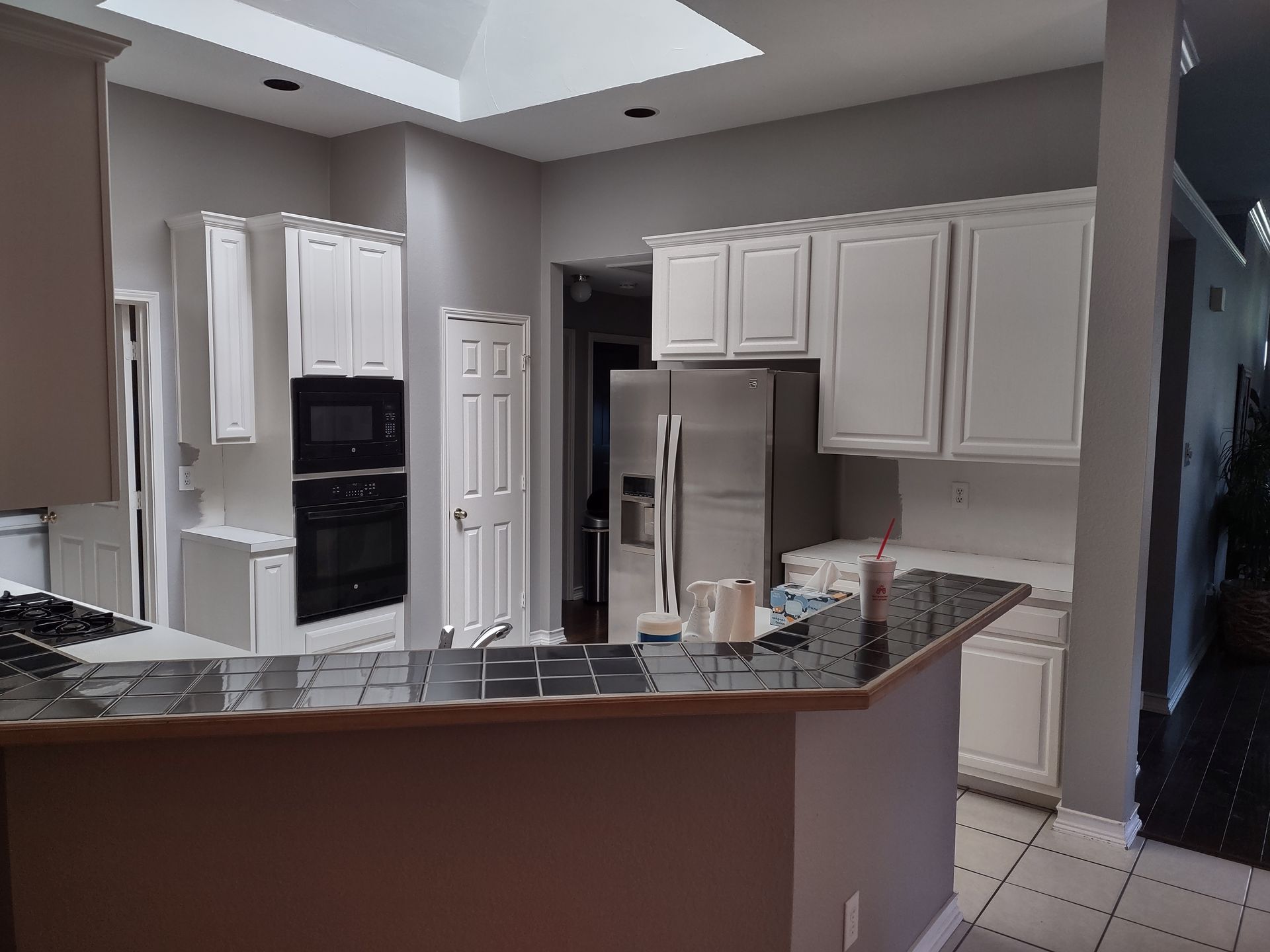 A kitchen with white cabinets and a stainless steel refrigerator