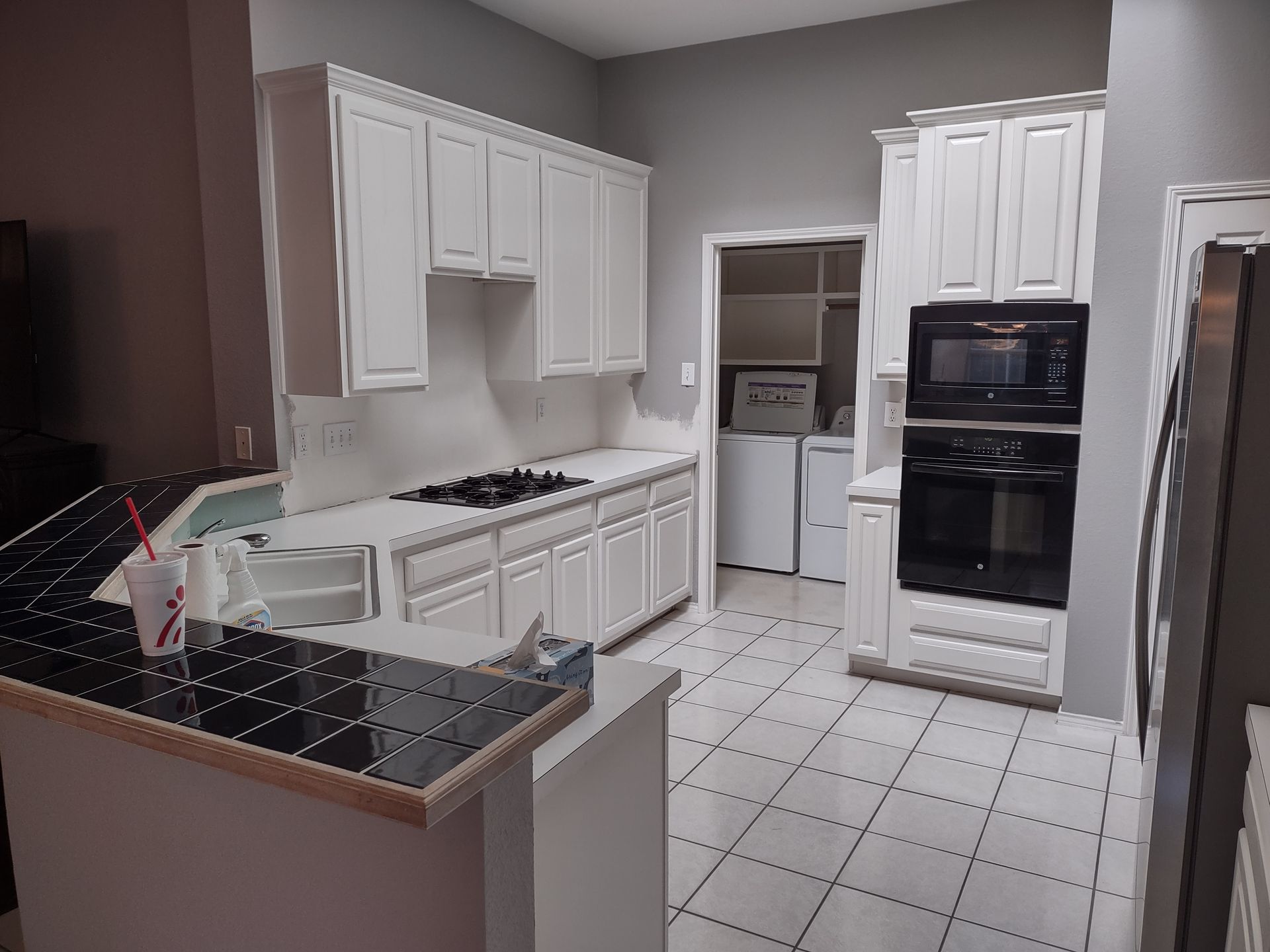 A kitchen with white cabinets and black counter tops