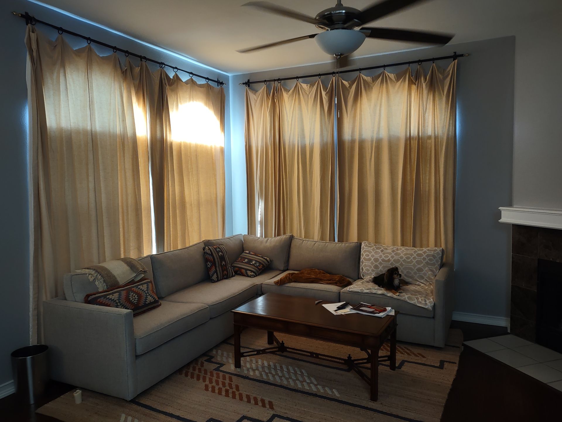 A living room with a sectional couch a coffee table and a ceiling fan