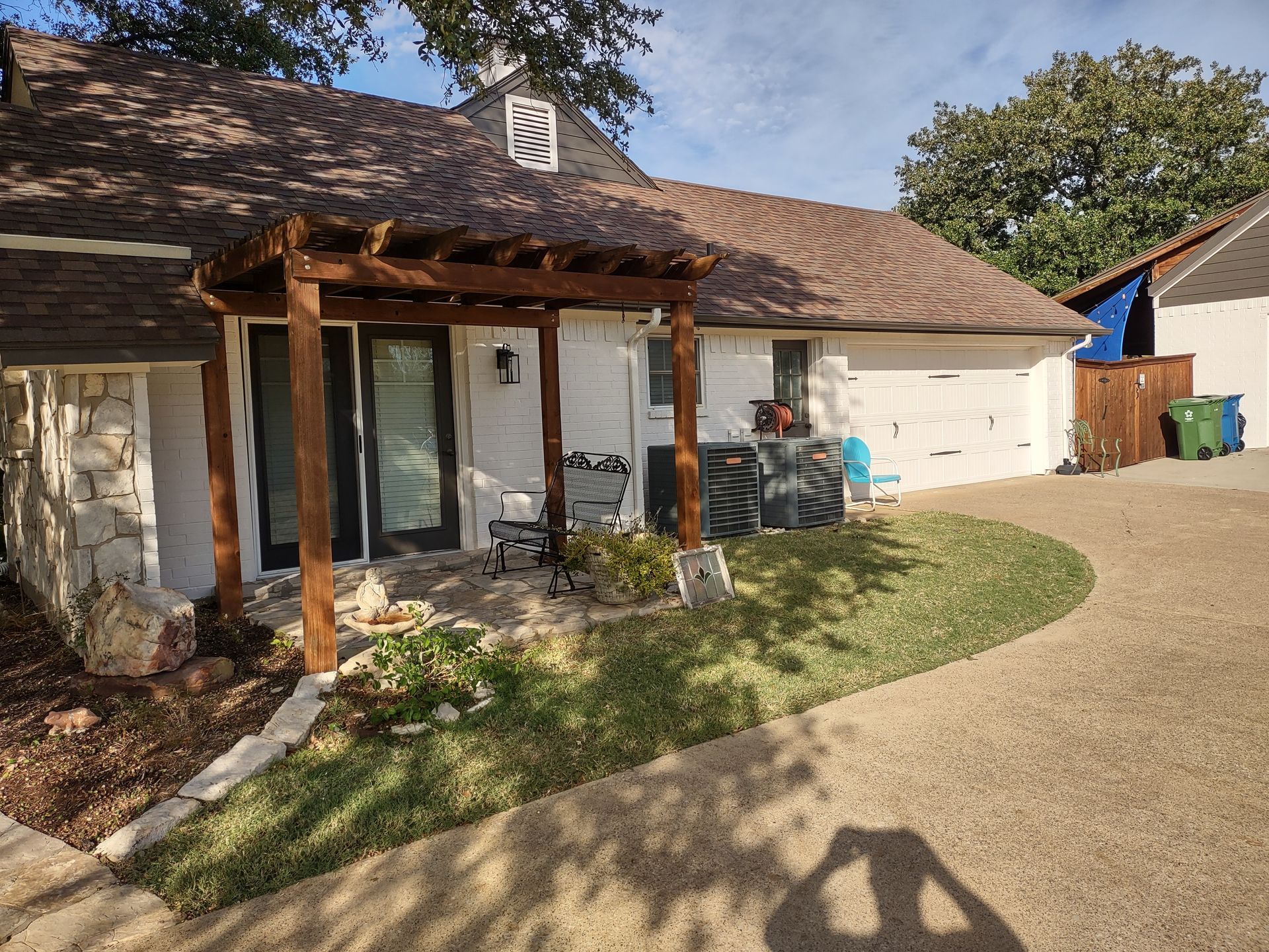 A white house with a wooden pergola in front of it.