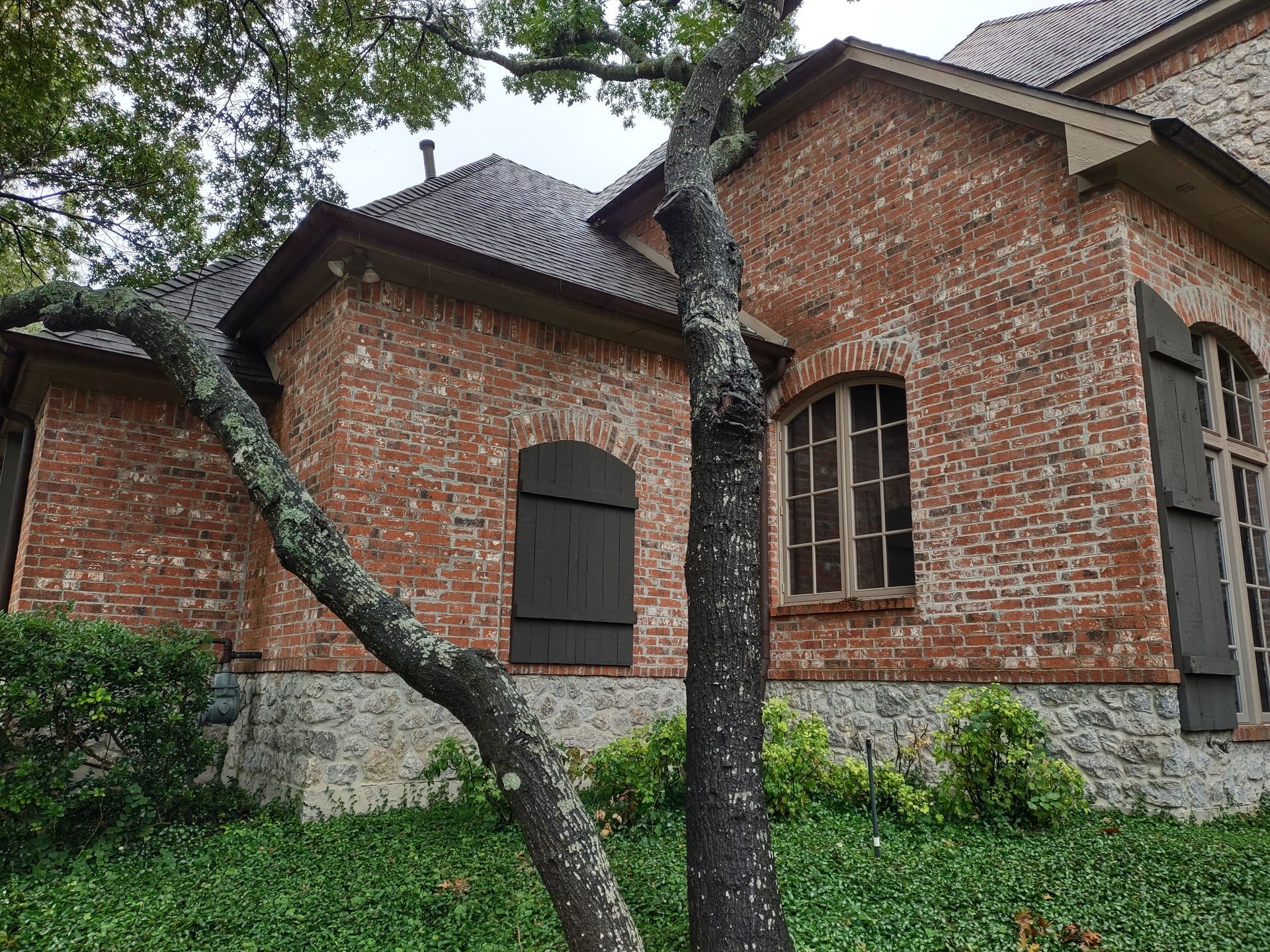 A large brick house with a tree in front of it.