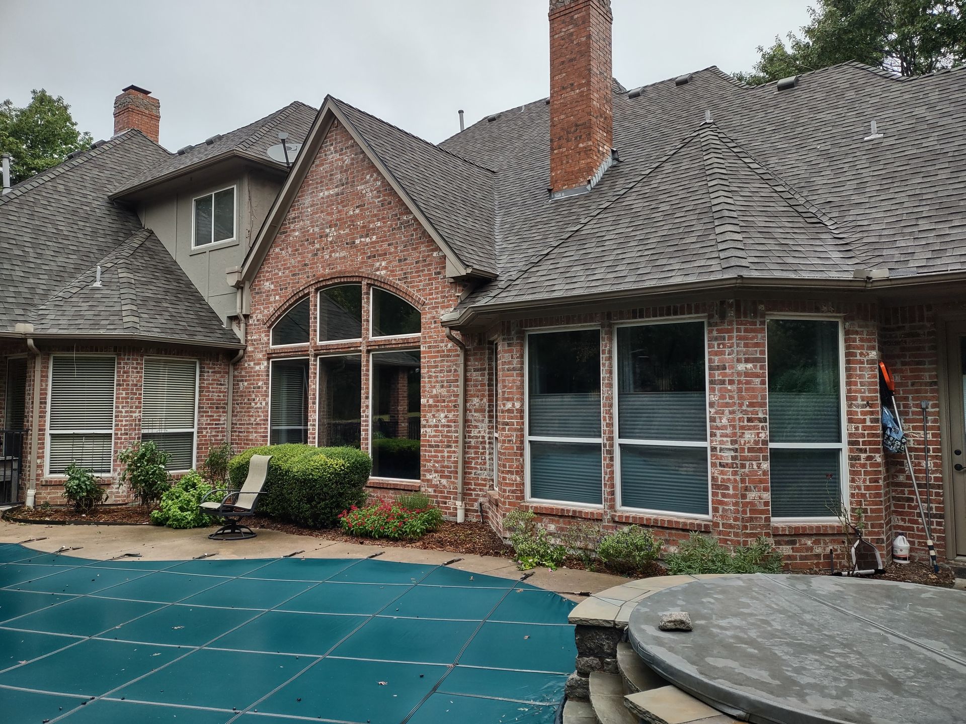 A large brick house with a swimming pool in front of it.