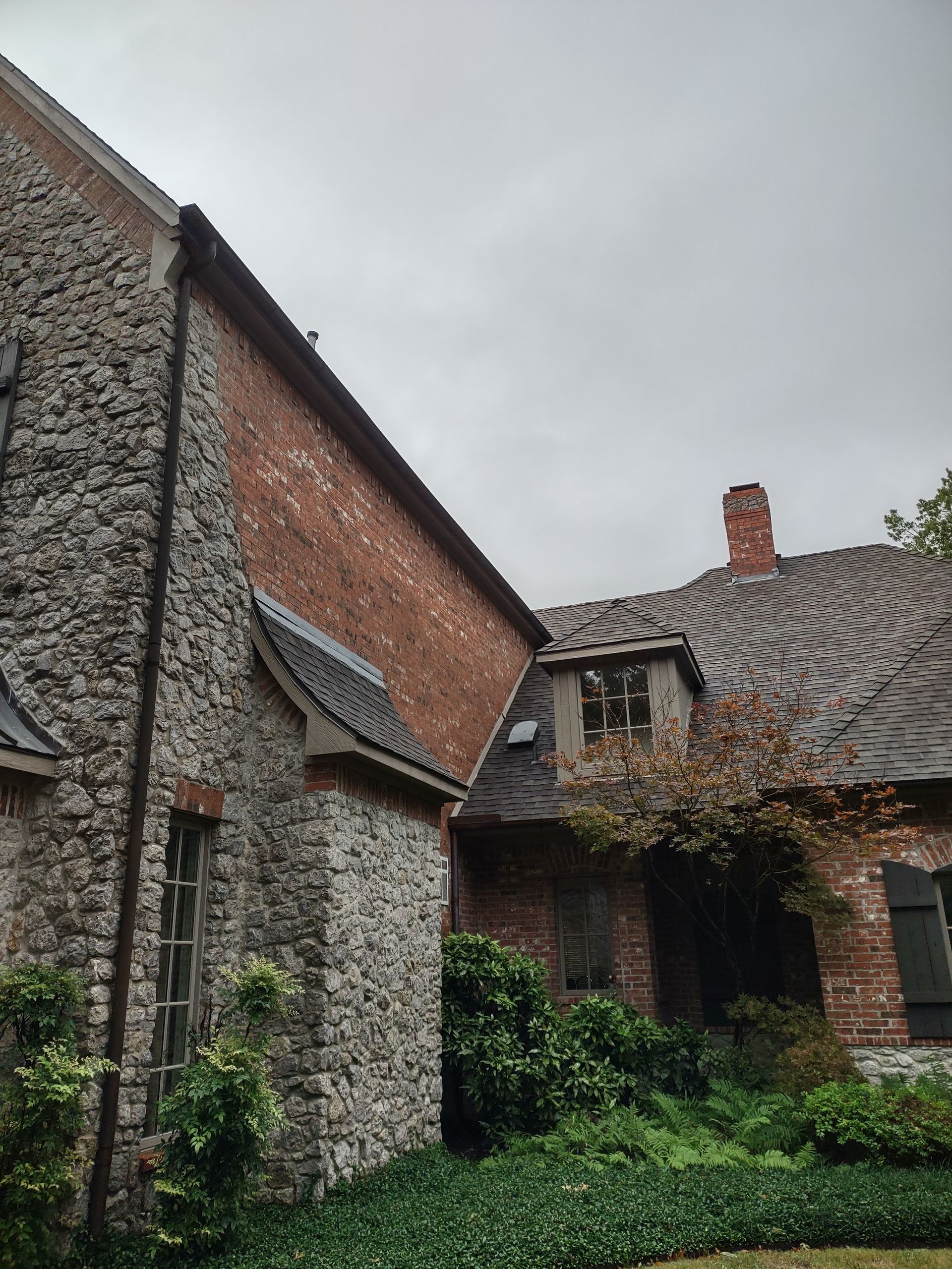 A large stone and brick house with a chimney on the roof.