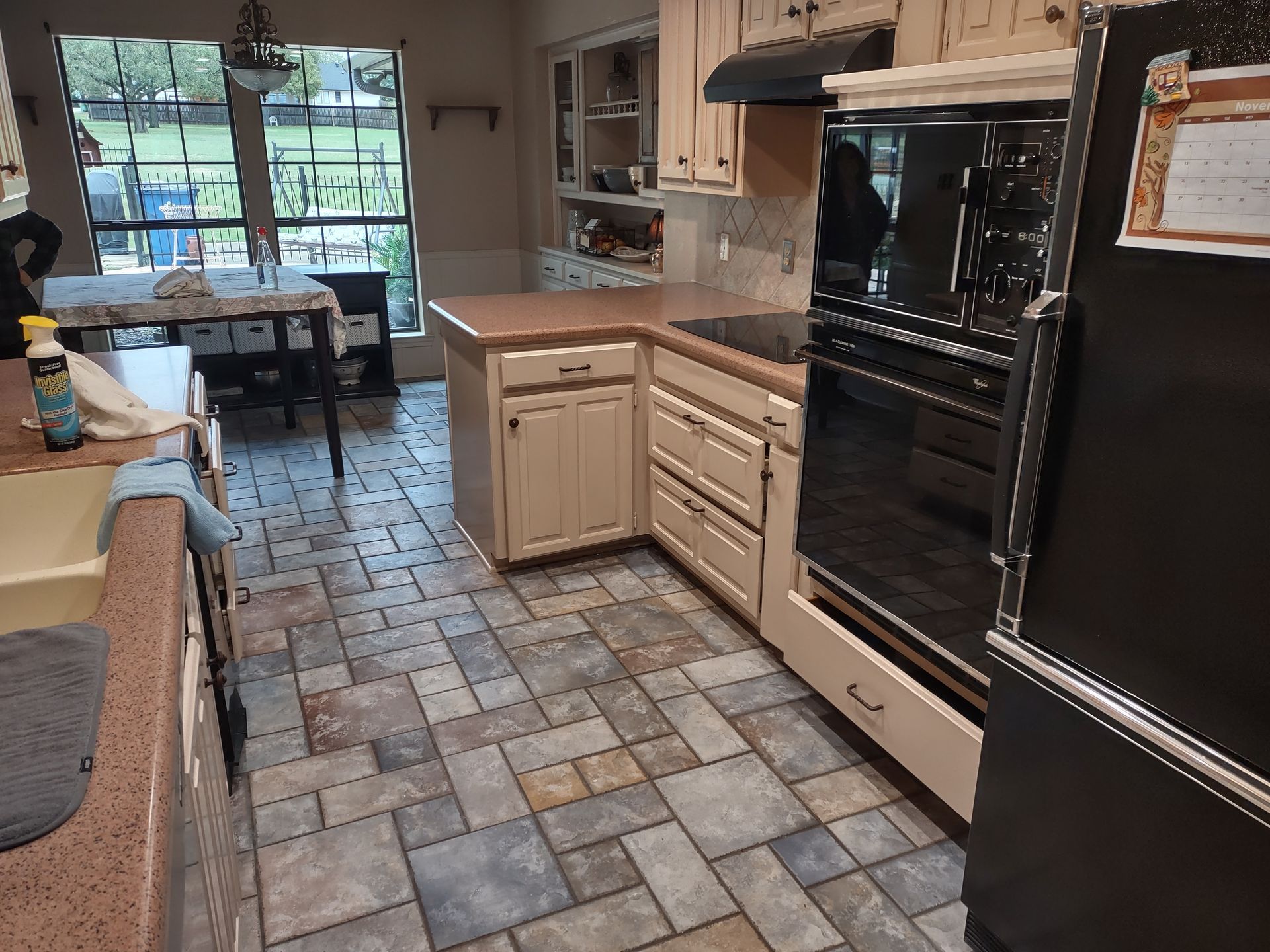 A kitchen with white cabinets and a black refrigerator