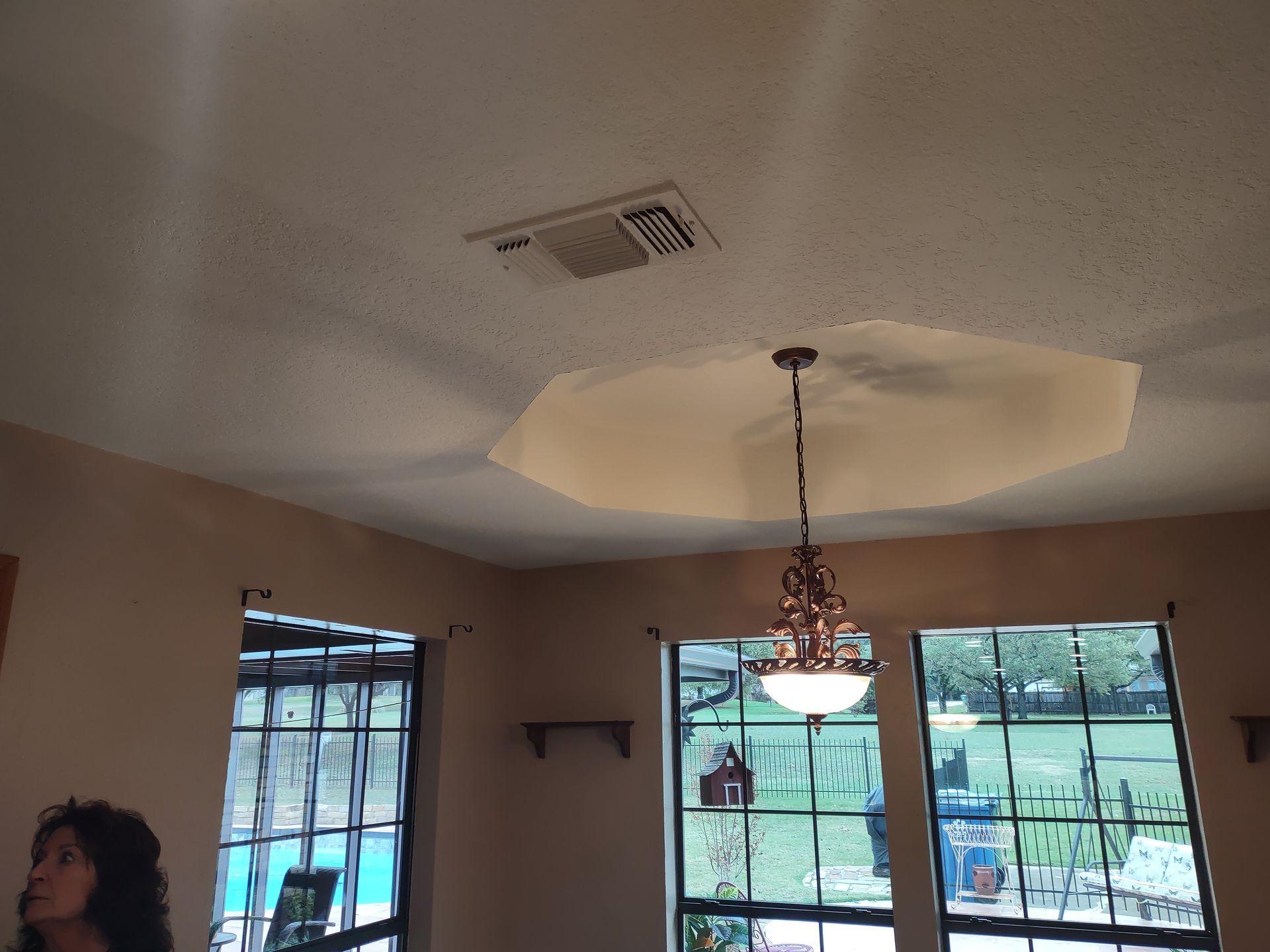 A woman stands in a room with a chandelier hanging from the ceiling