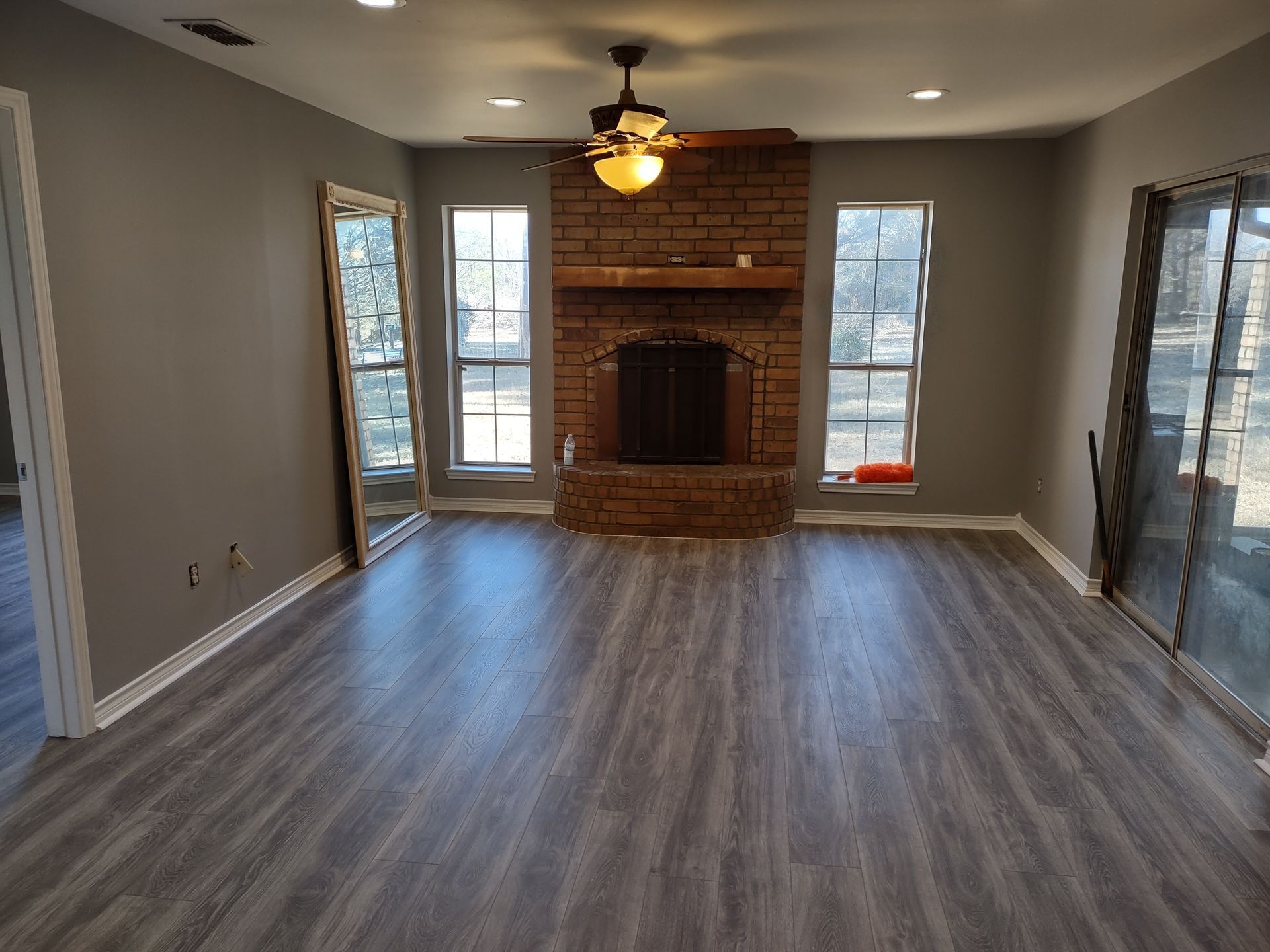 A living room with a fireplace and a ceiling fan.