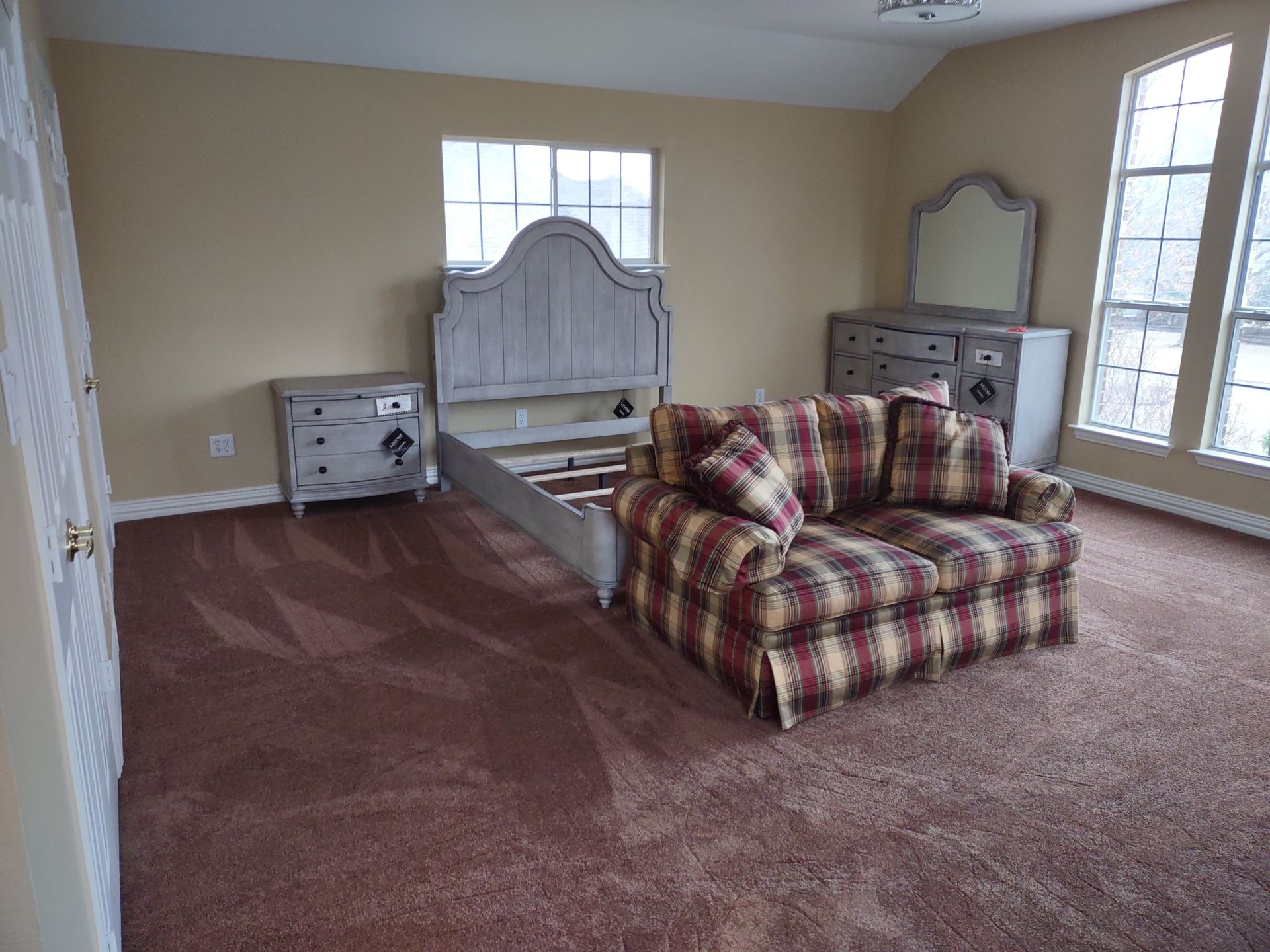 A bedroom with a bed , couch , dresser and mirror.