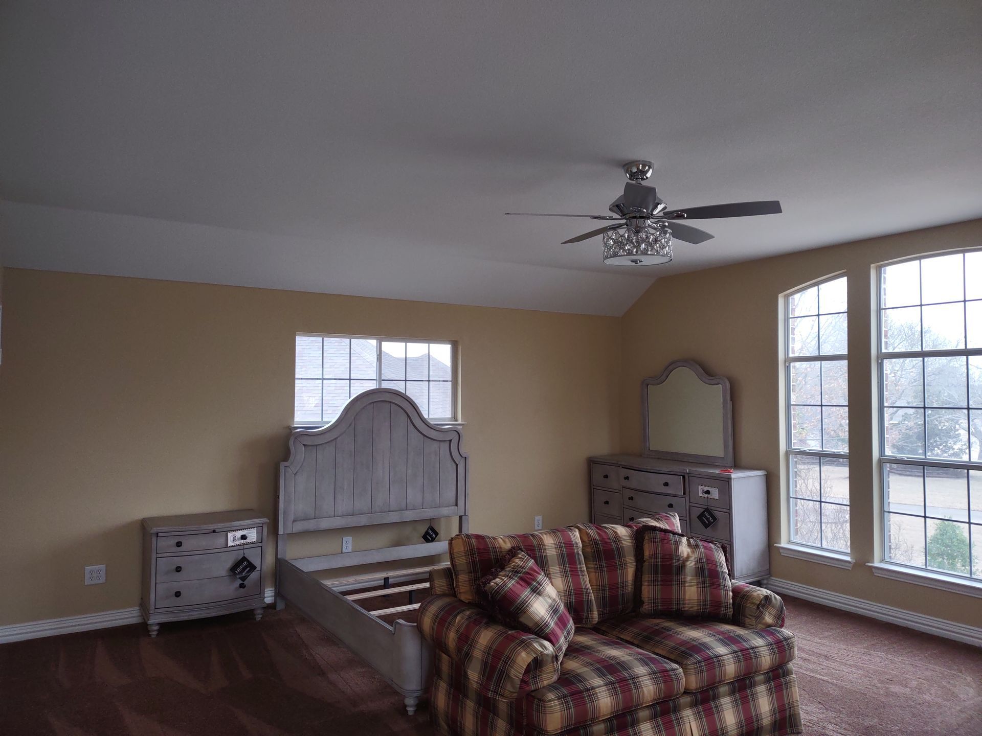 A bedroom with a couch and a bed and a ceiling fan