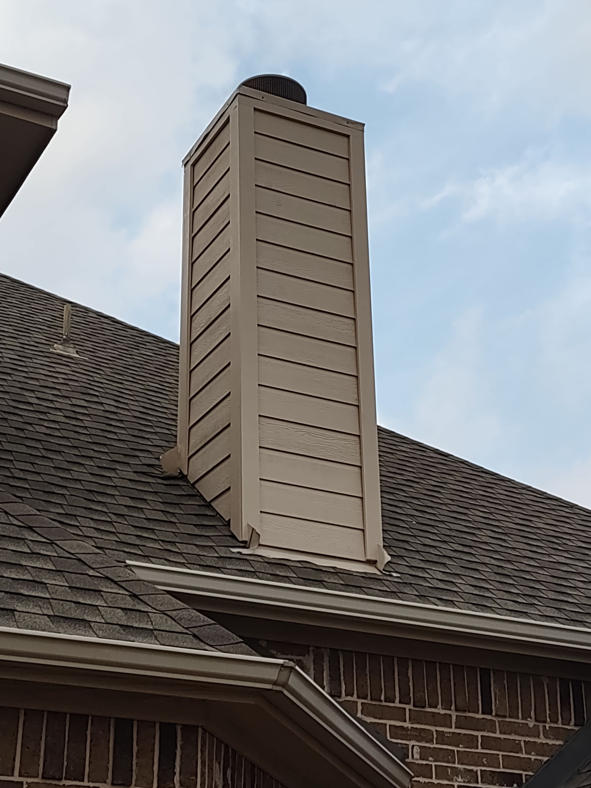A chimney on the roof of a brick house