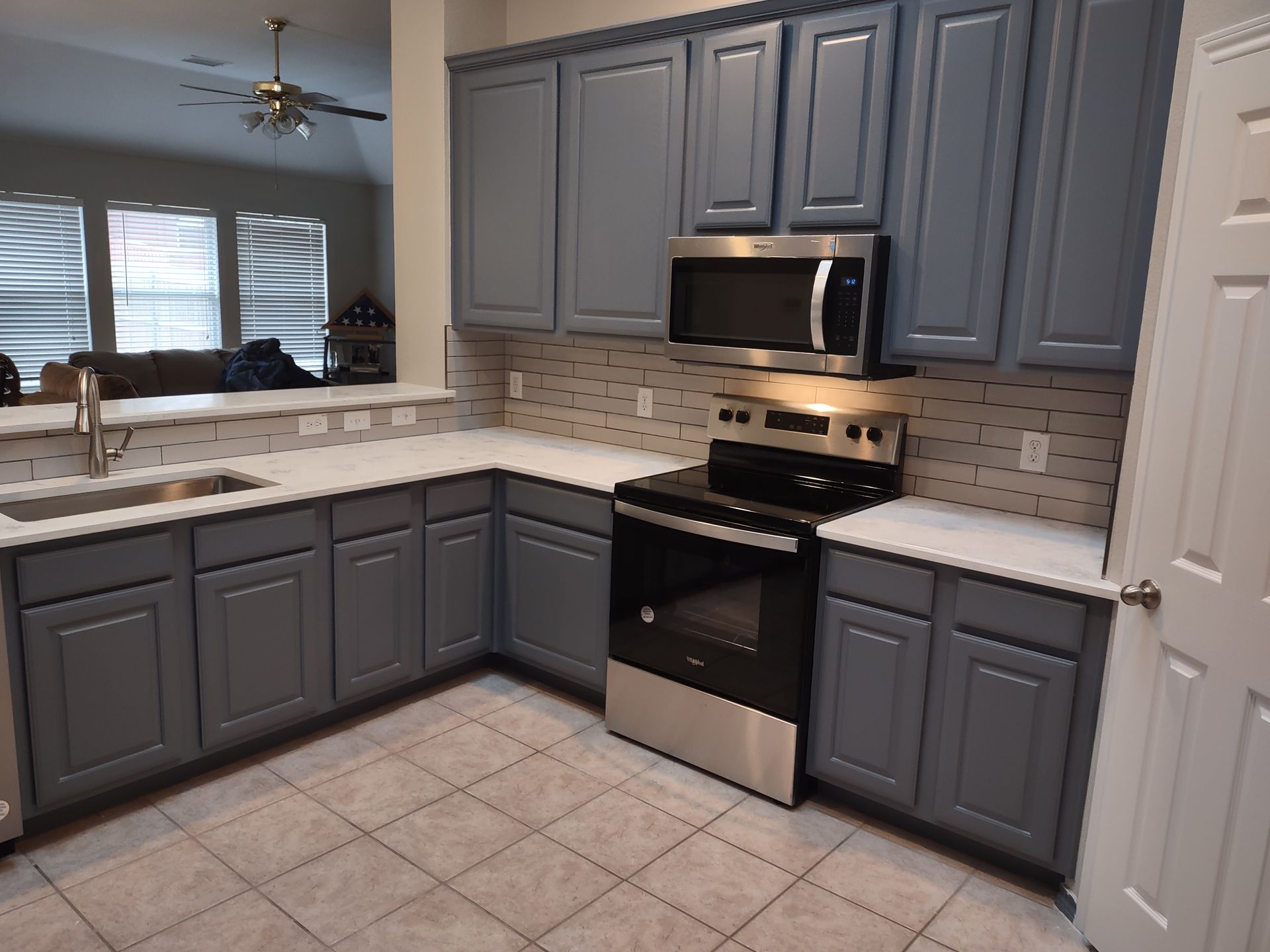 A kitchen with gray cabinets and stainless steel appliances