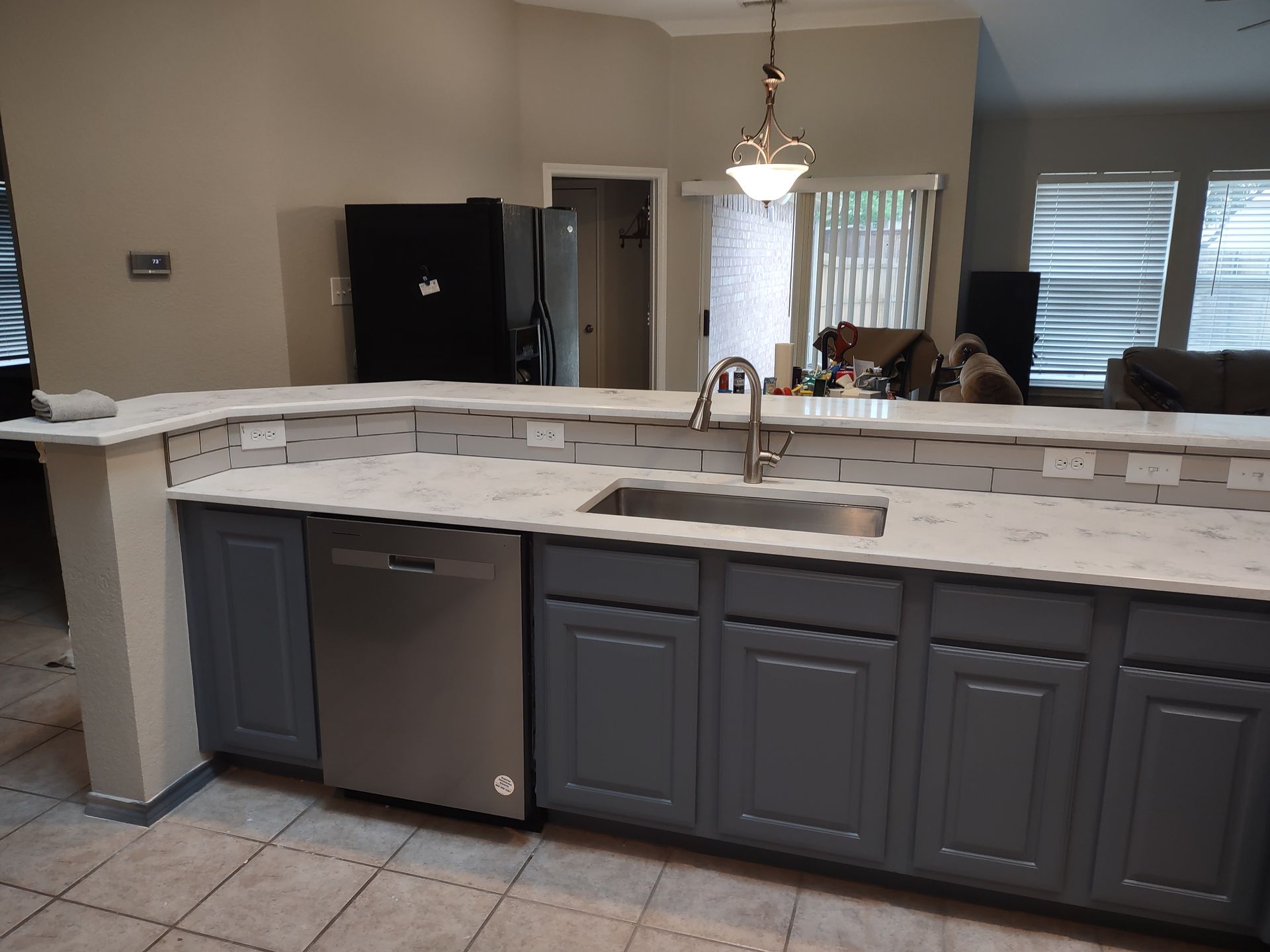 A kitchen with gray cabinets and a stainless steel dishwasher