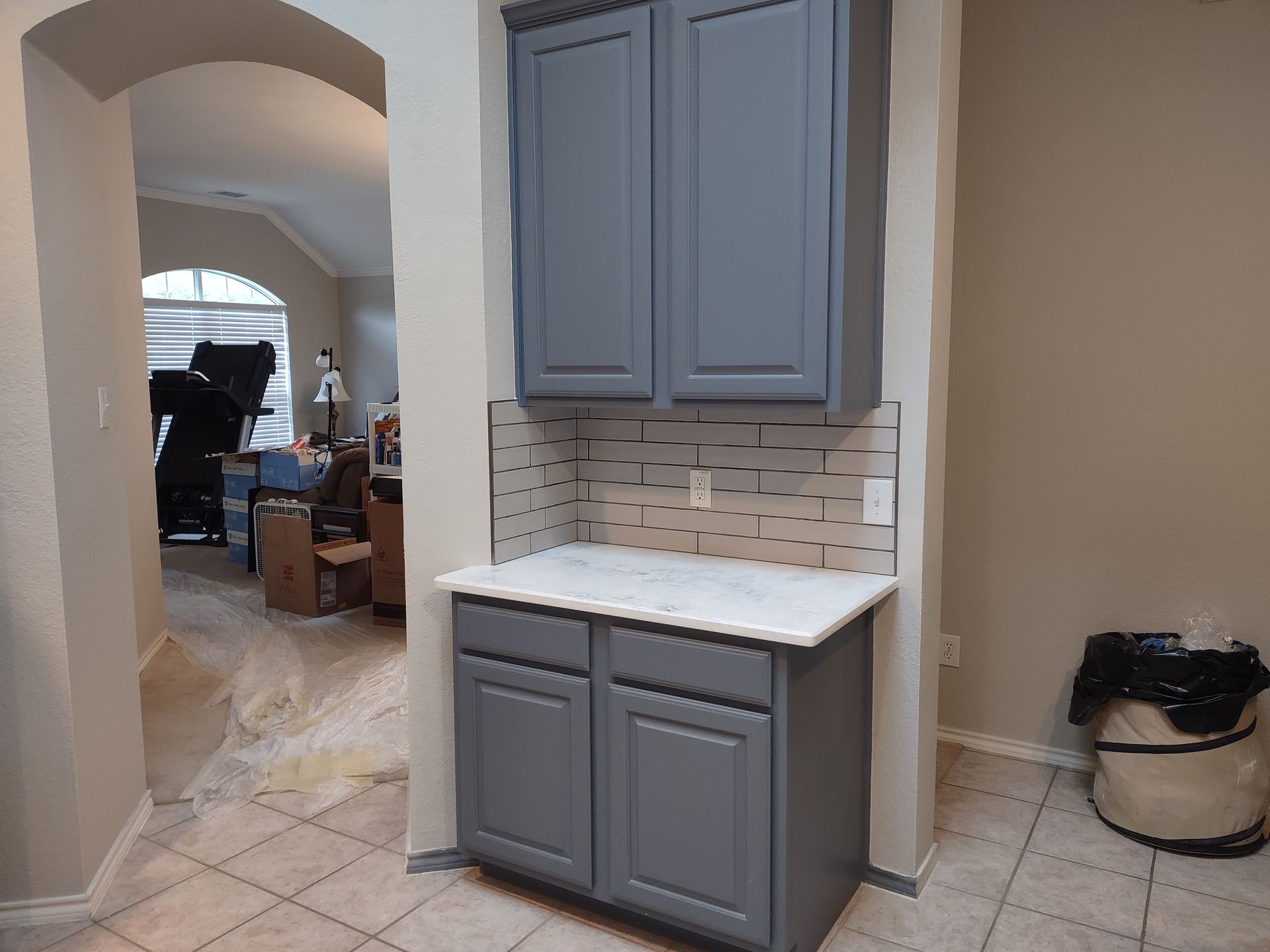 A kitchen with gray cabinets and a white counter top.