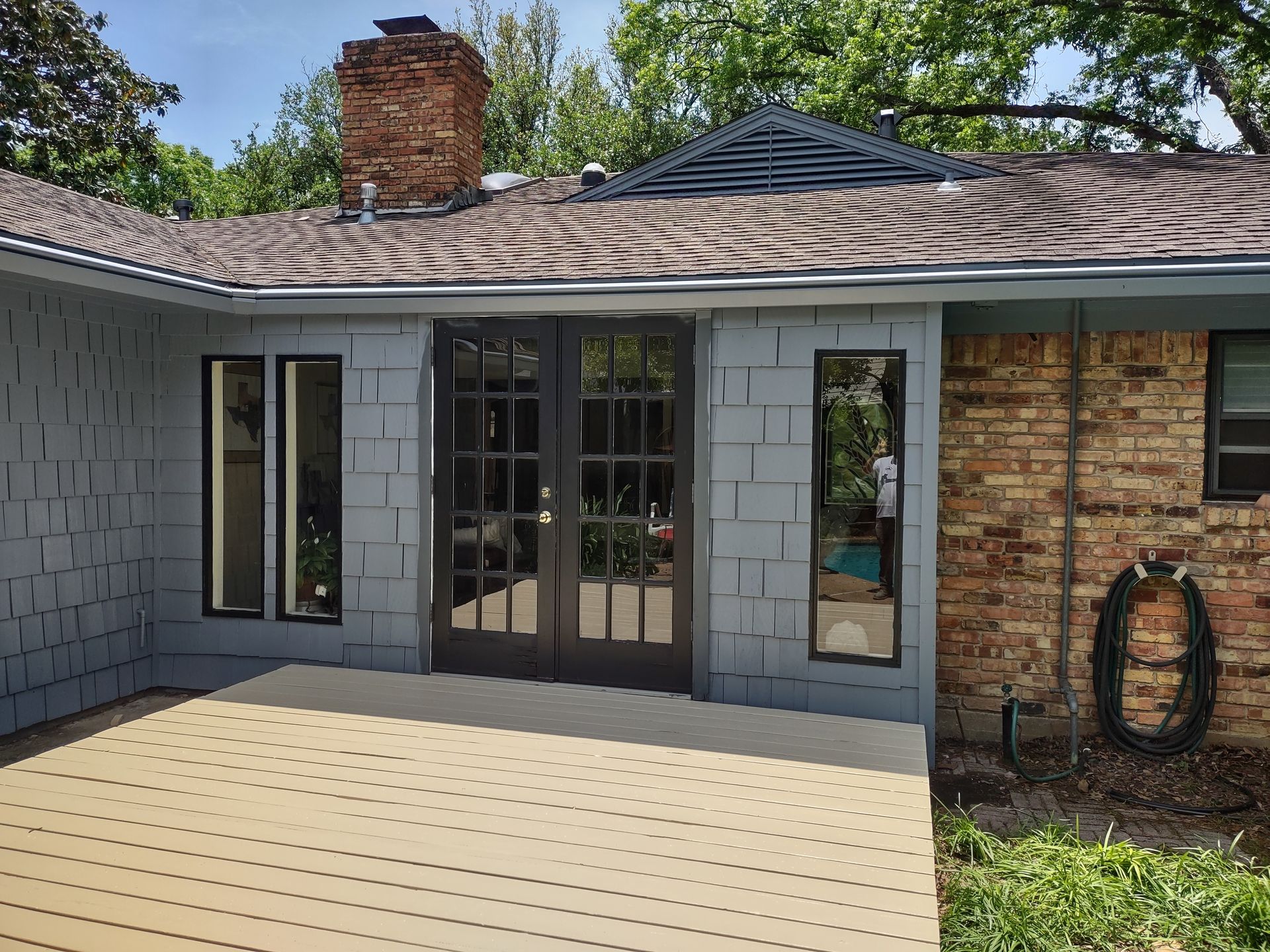 The back of a brick house with a patio and sliding glass doors.