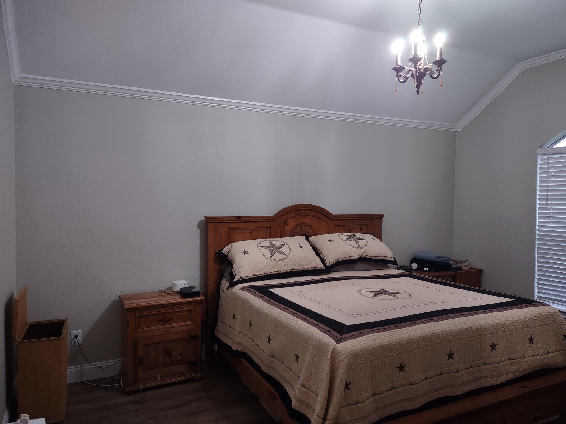 A bedroom with a bed , nightstands , and a chandelier.