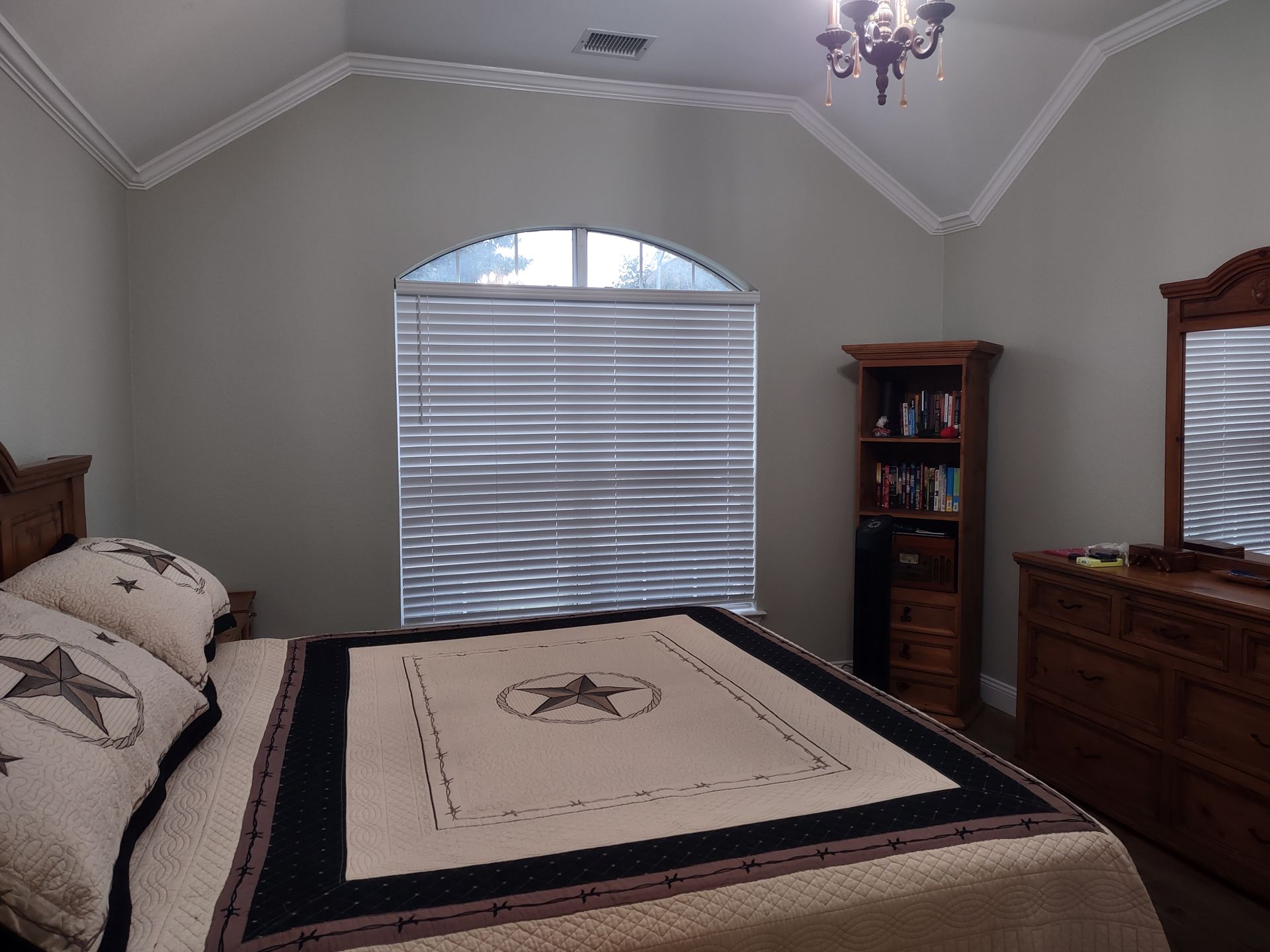 A bedroom with a bed dresser mirror and window