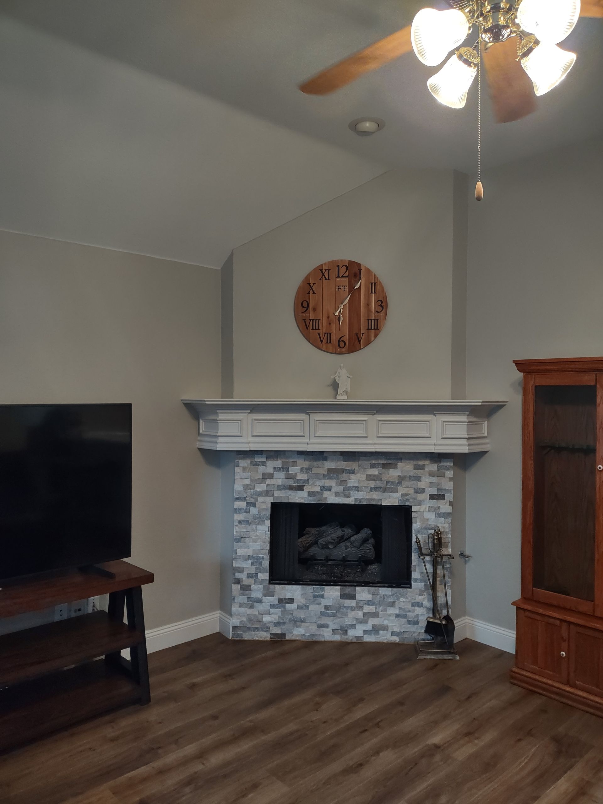 A living room with a fireplace and a ceiling fan