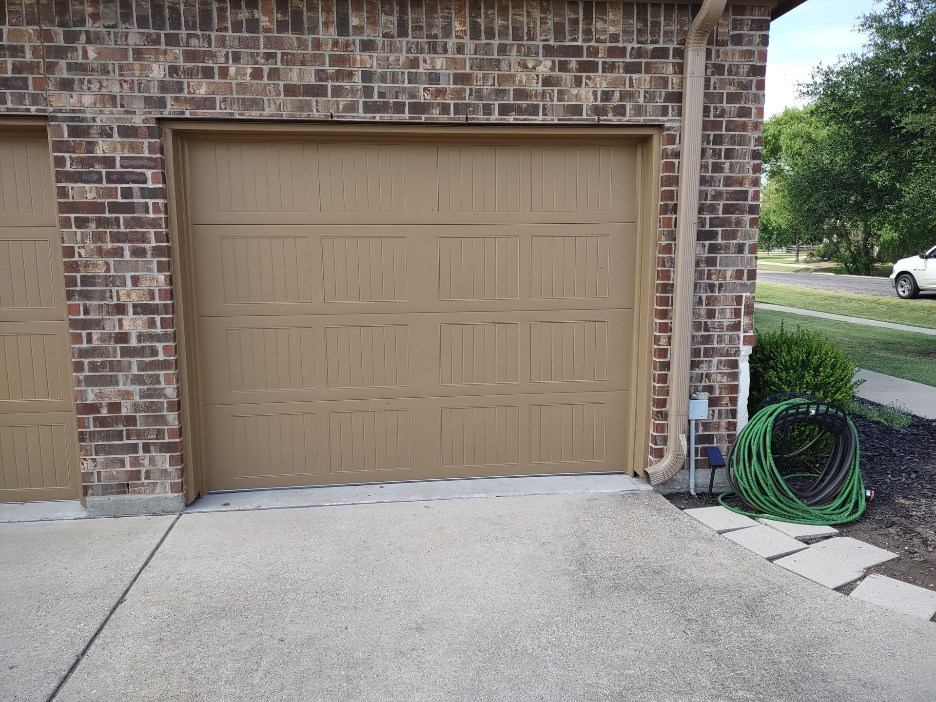 A garage door with a green hose next to it