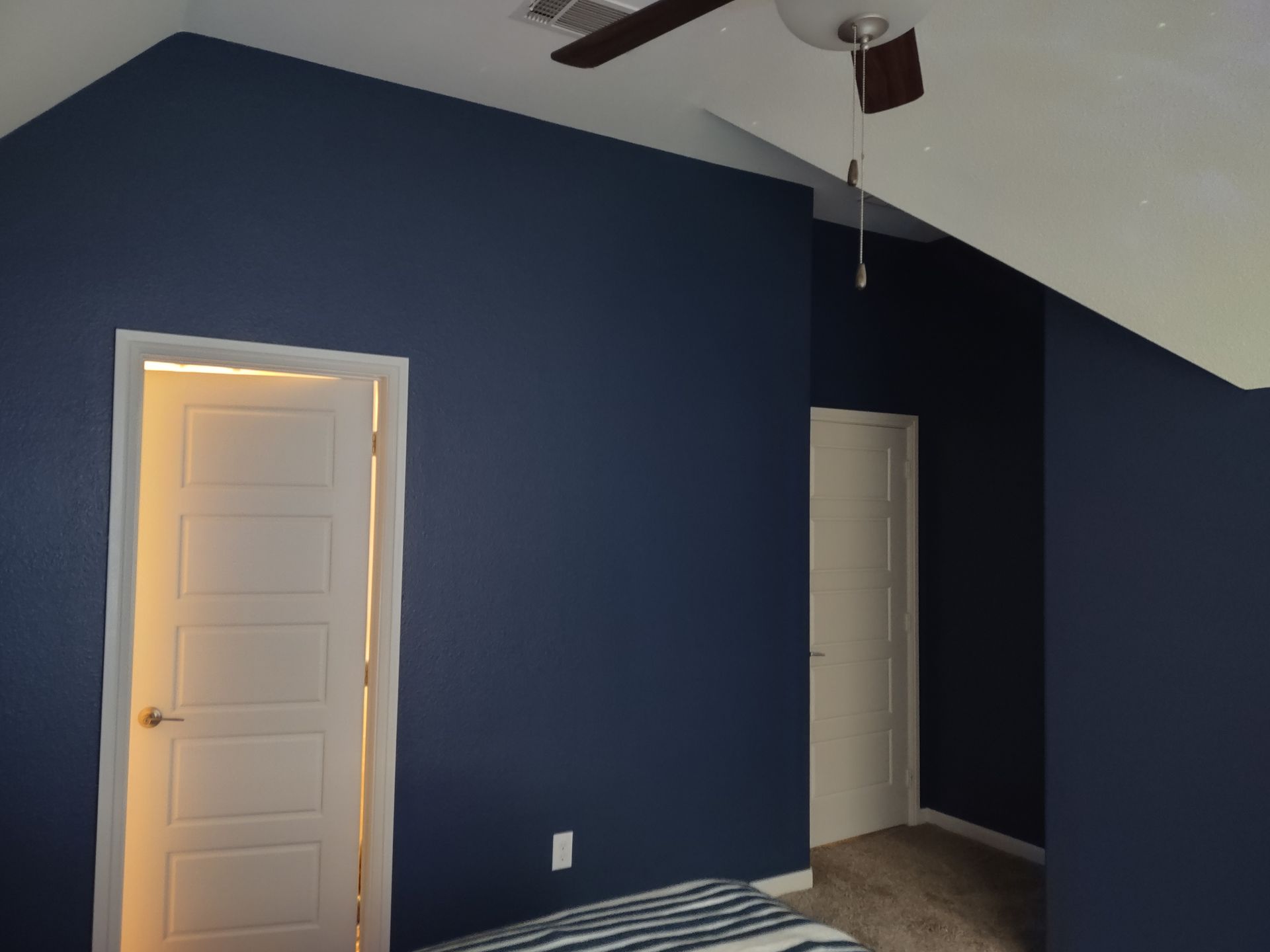 A bedroom with blue walls and a ceiling fan