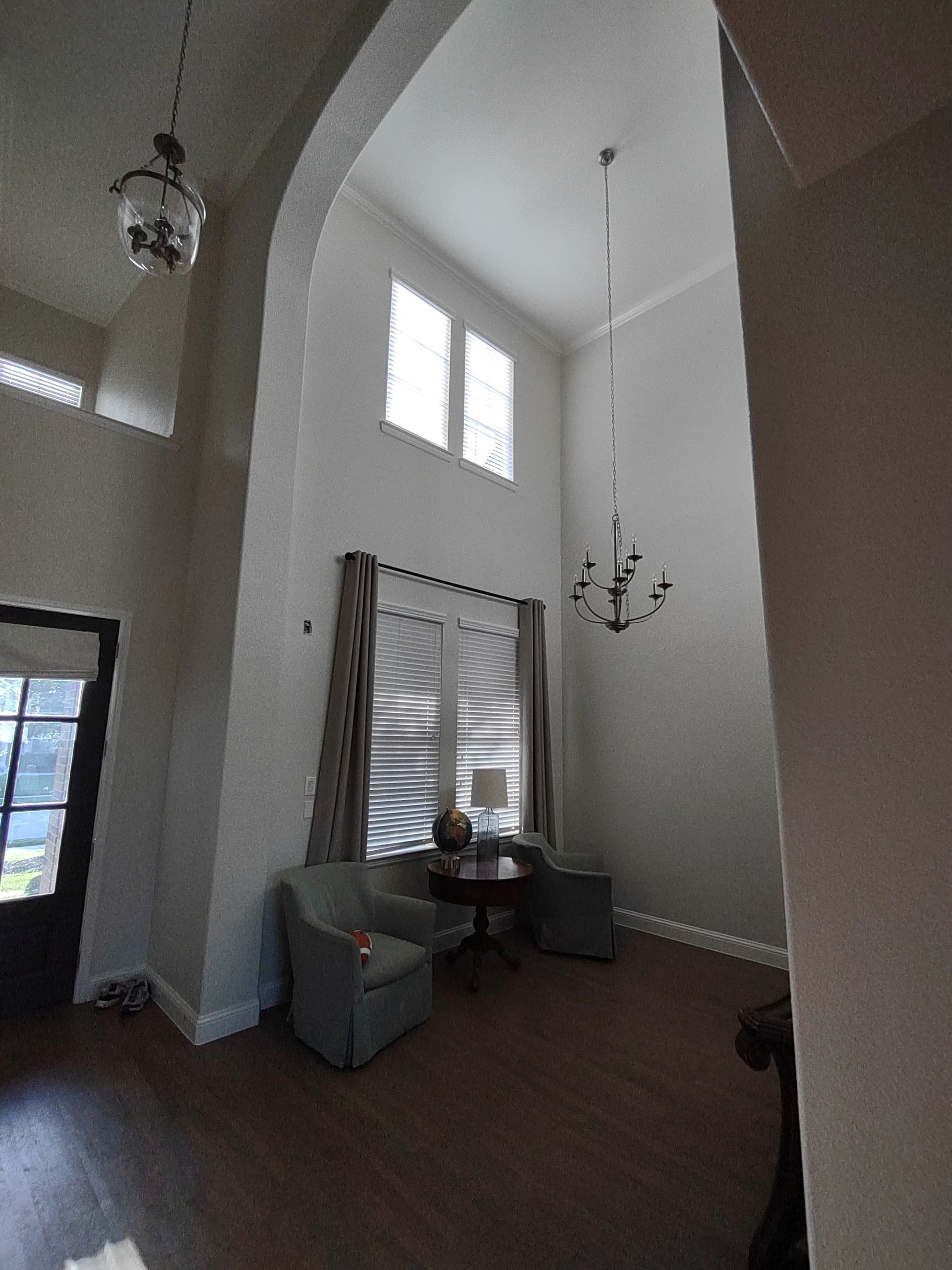 A living room with two chairs , a table and a chandelier.