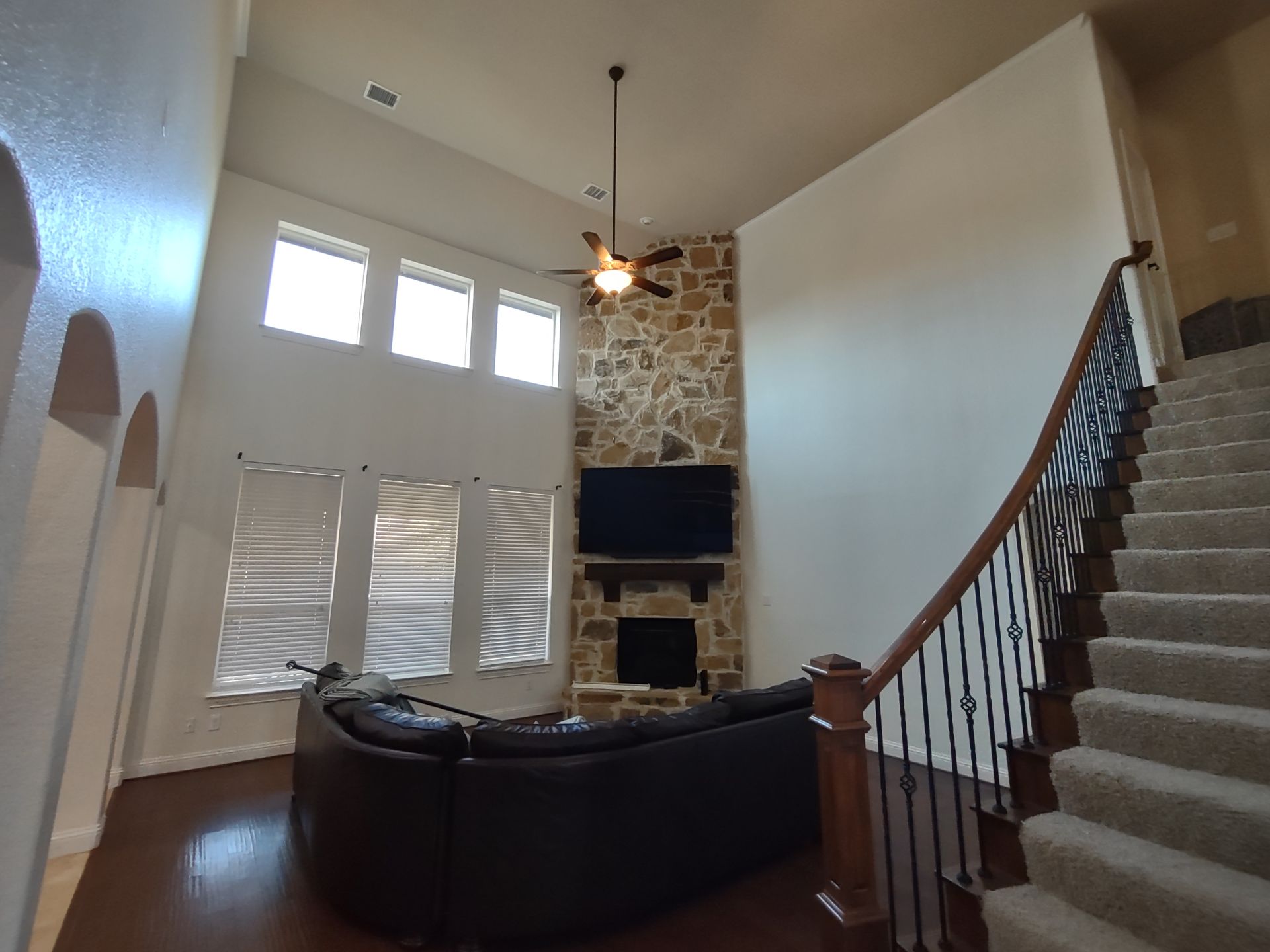 A living room with a couch , fireplace , television and stairs.