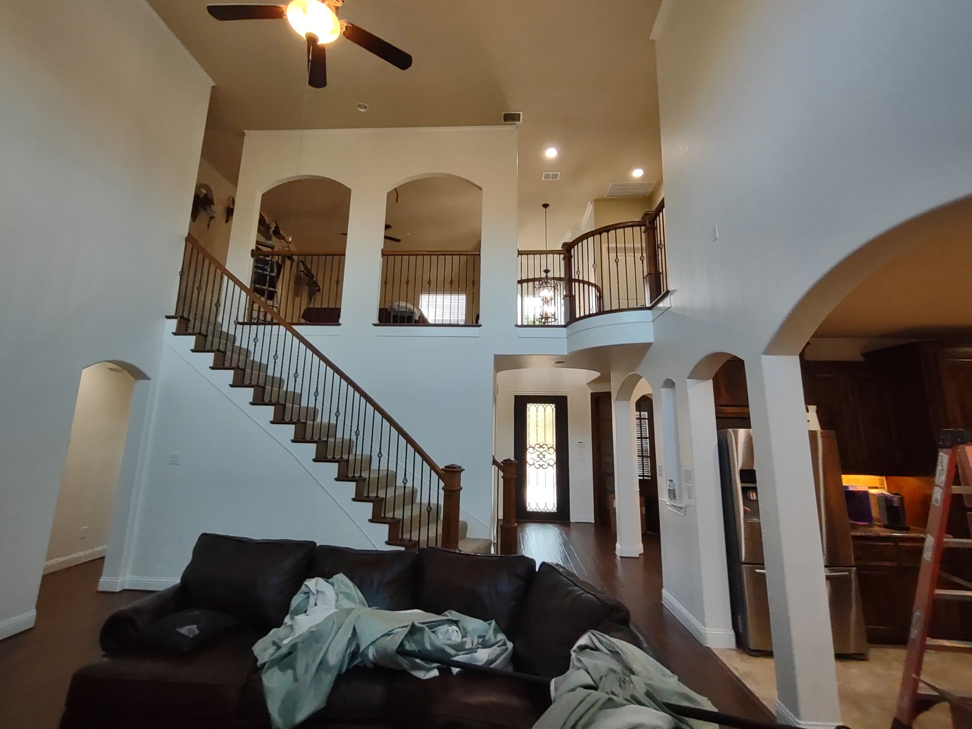 A living room with a couch , stairs and a ceiling fan.
