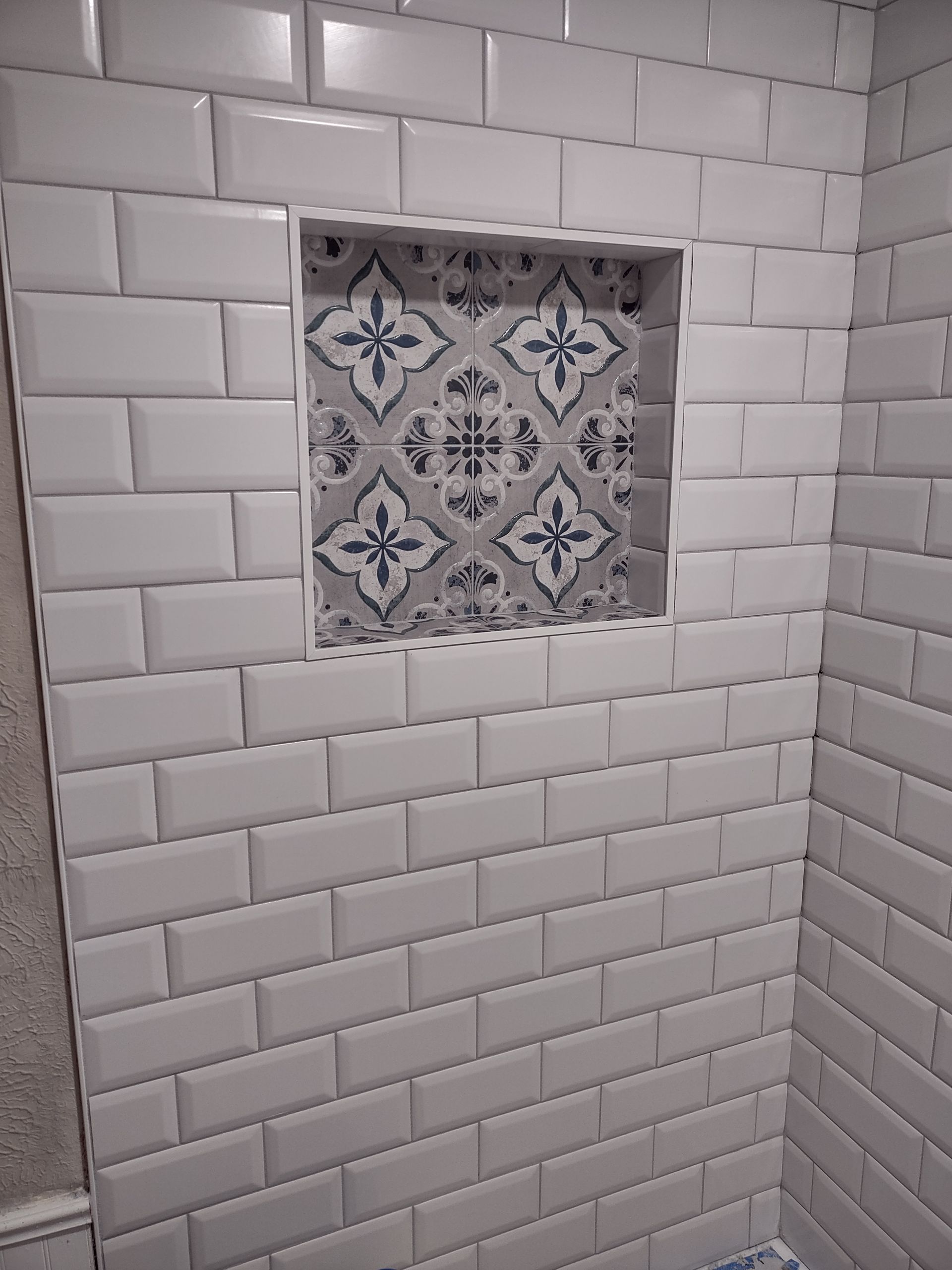 A bathroom with white tiles and a niche in the wall.